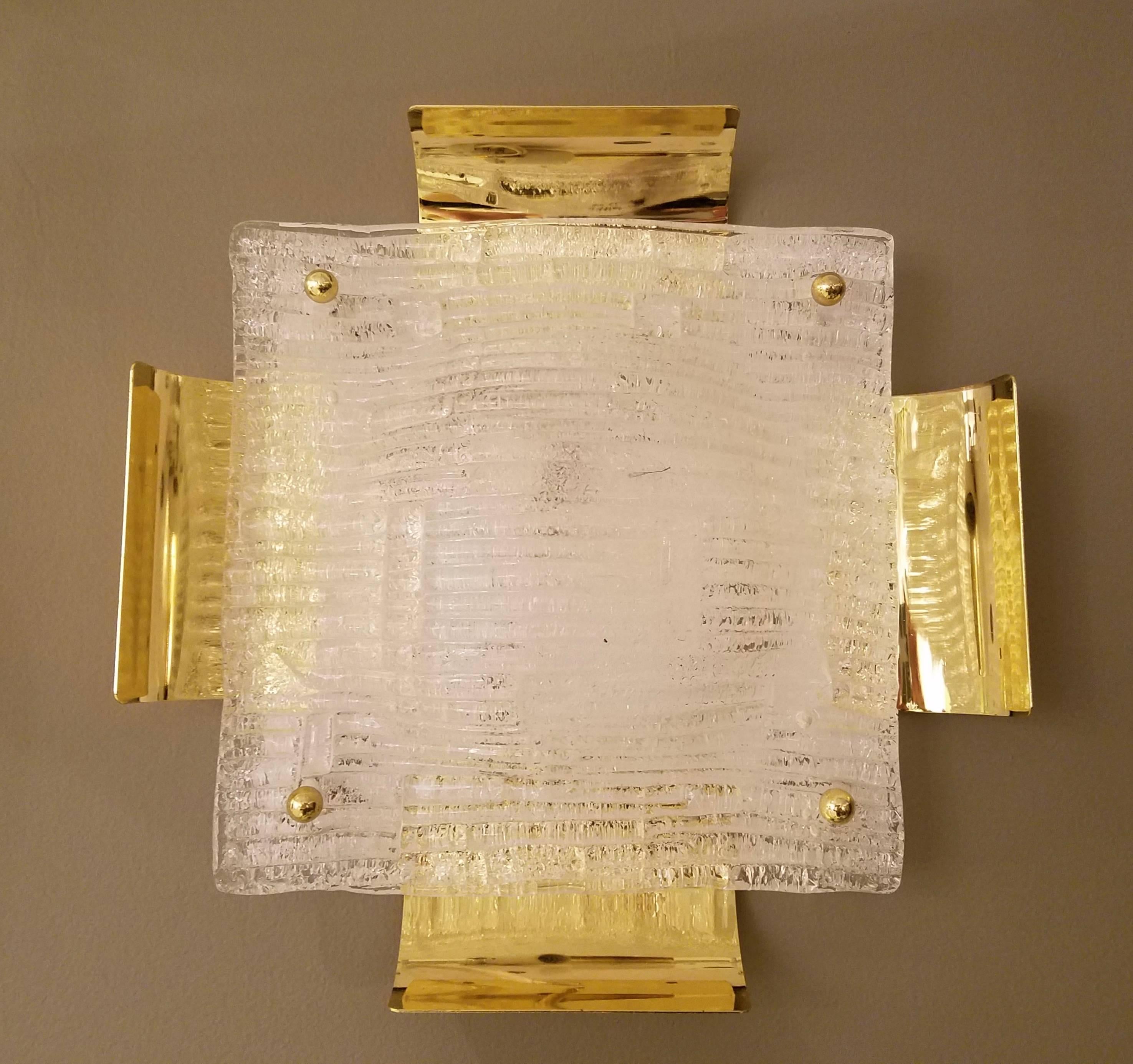A large pair of 14" Austrian Mid-Century sconces by Kalmar comprised of handblown square ribbed glass panels with rectangular concave brass sheets extending from each side from a white matte back plate held together with four brass screws, with