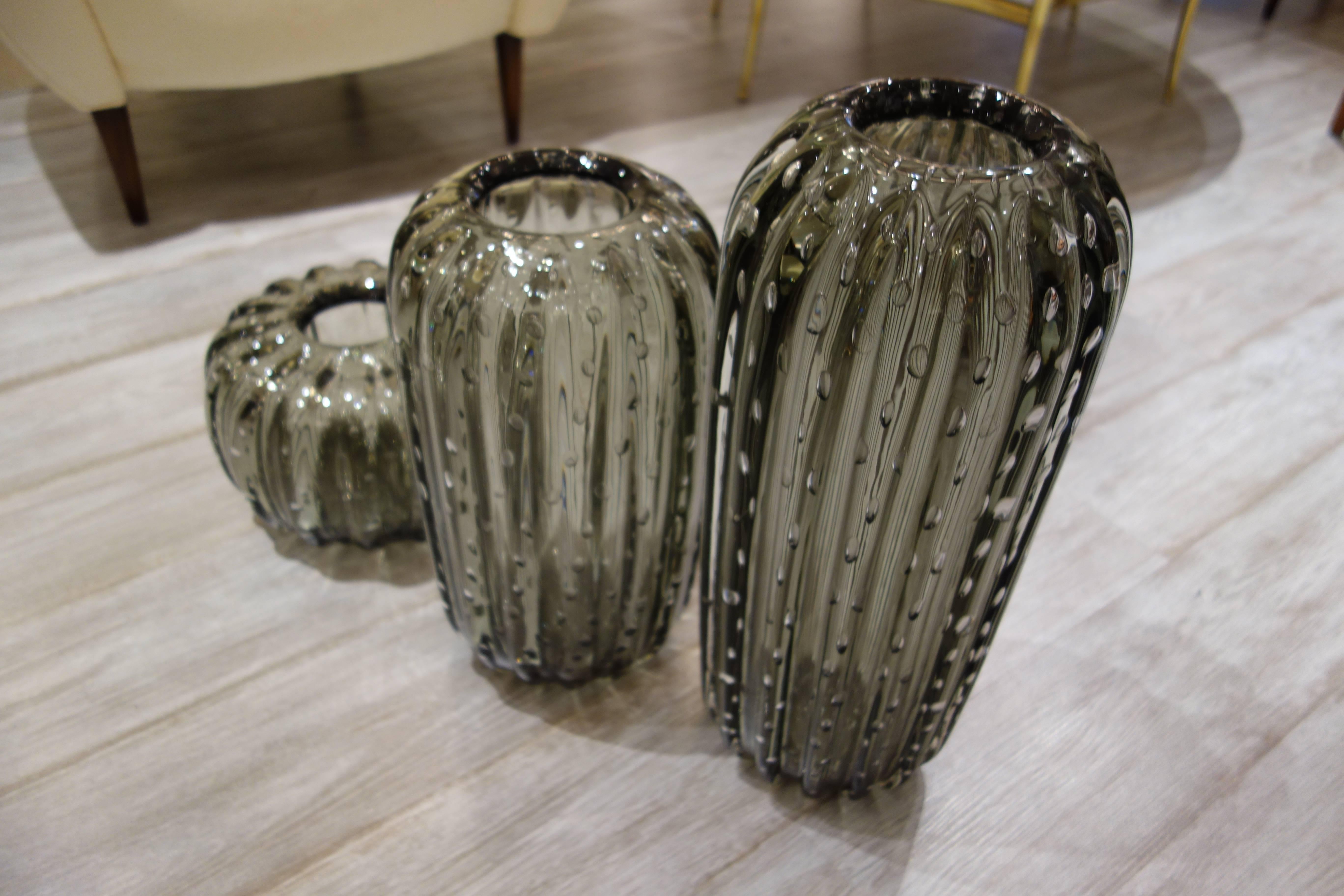 A set of three handblown thick, heavy vases or vessels by Alberto Dona in transparent gray Murano glass with controlled bubbles, signed on the bottom. The dimensions of the largest piece is listed below, the medium size vase is 14.5
