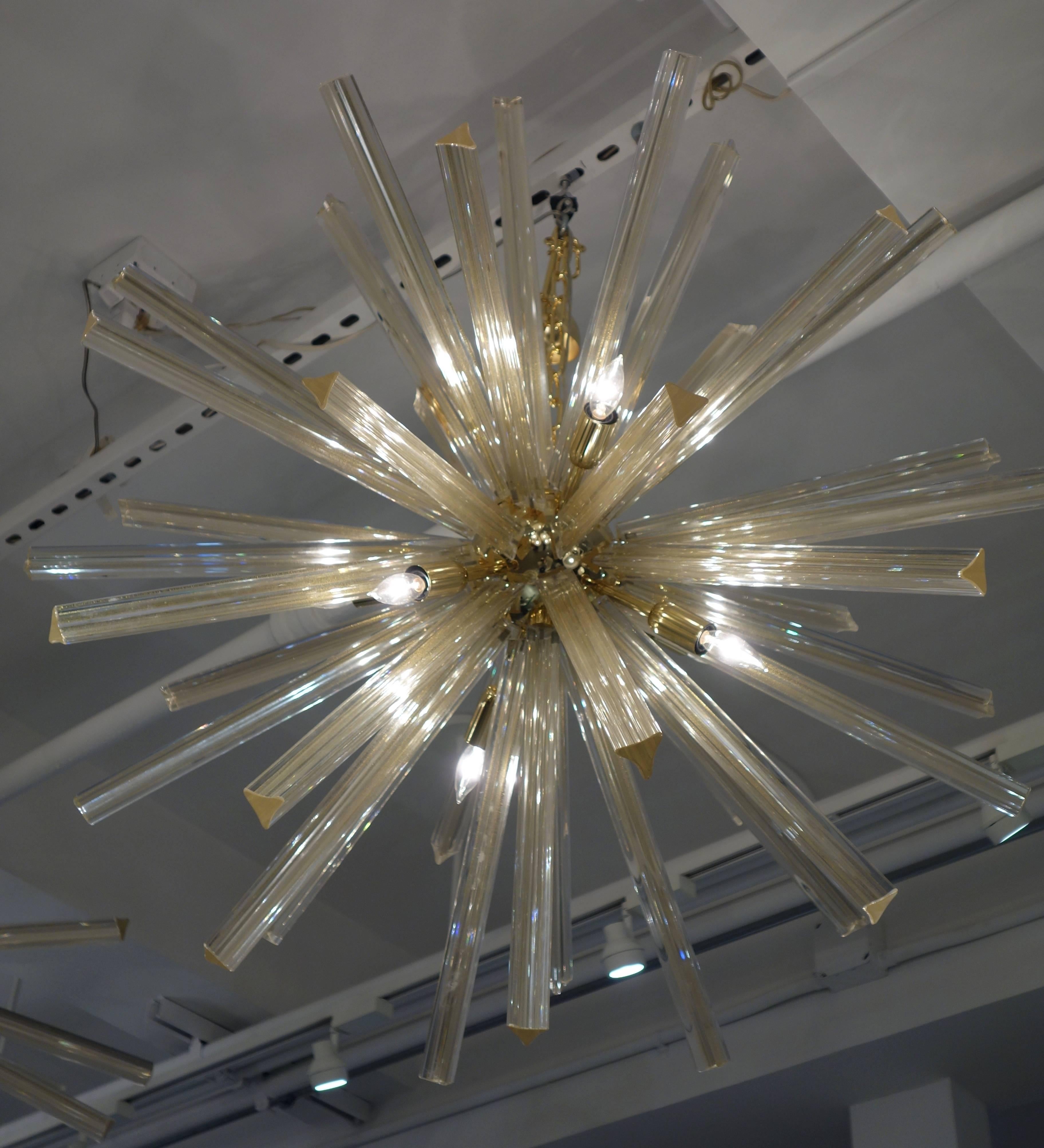An Italian Murano glass Sputnik chandelier each of the 40, 16 inch long triedi spikes of clear glass infused with real gold dust radiating from a brass orb with nine candelabra light sockets wired for the American market suspended from a brass chain