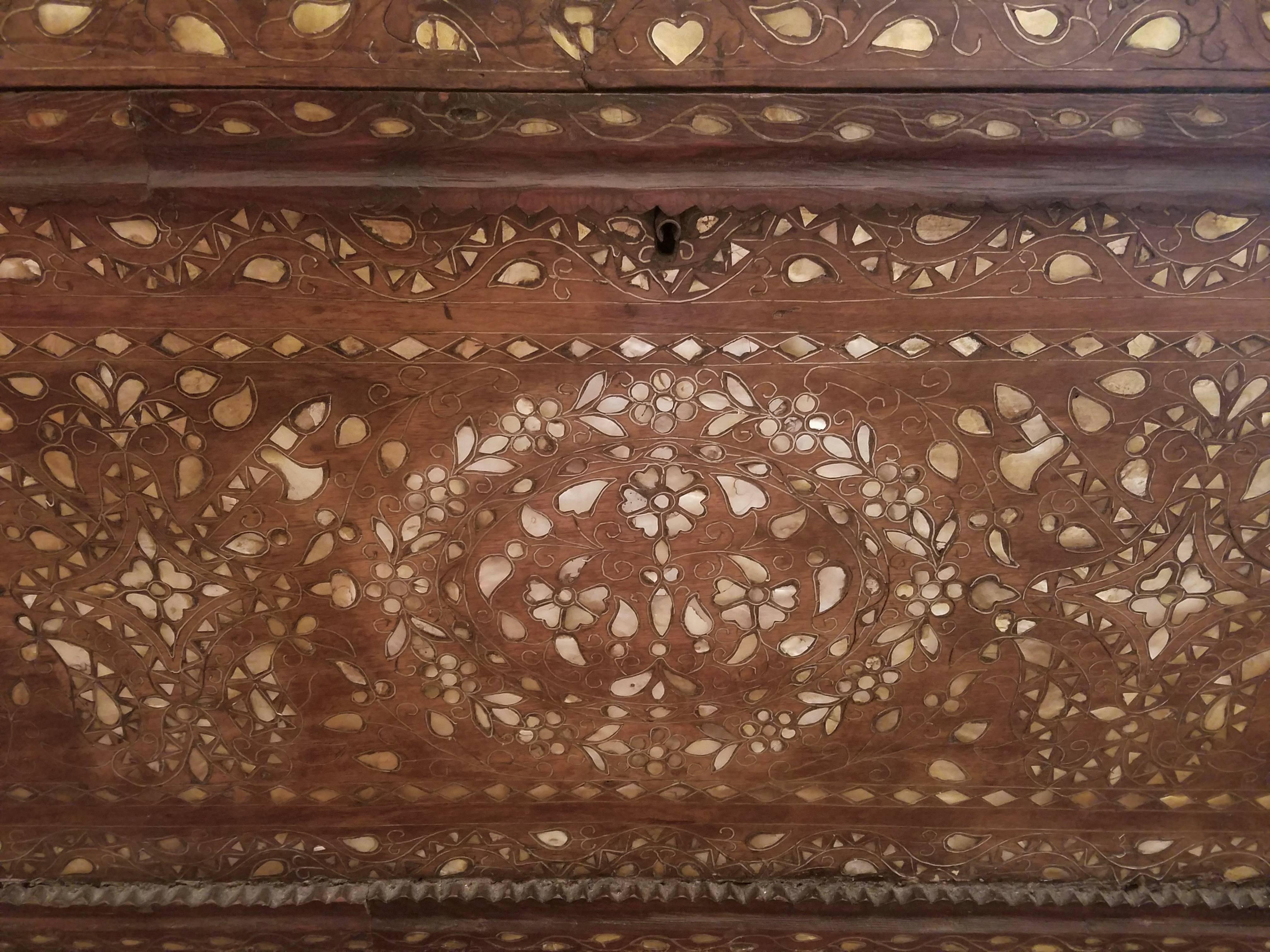 A large 19th century Syrian trunk profusely inlaid with mother-of-pearl and metal strapping on the front with sparser design on the sides, the back unadorned, the hinged top lifts to a spacious interior with two shallow open side sections each 4.5