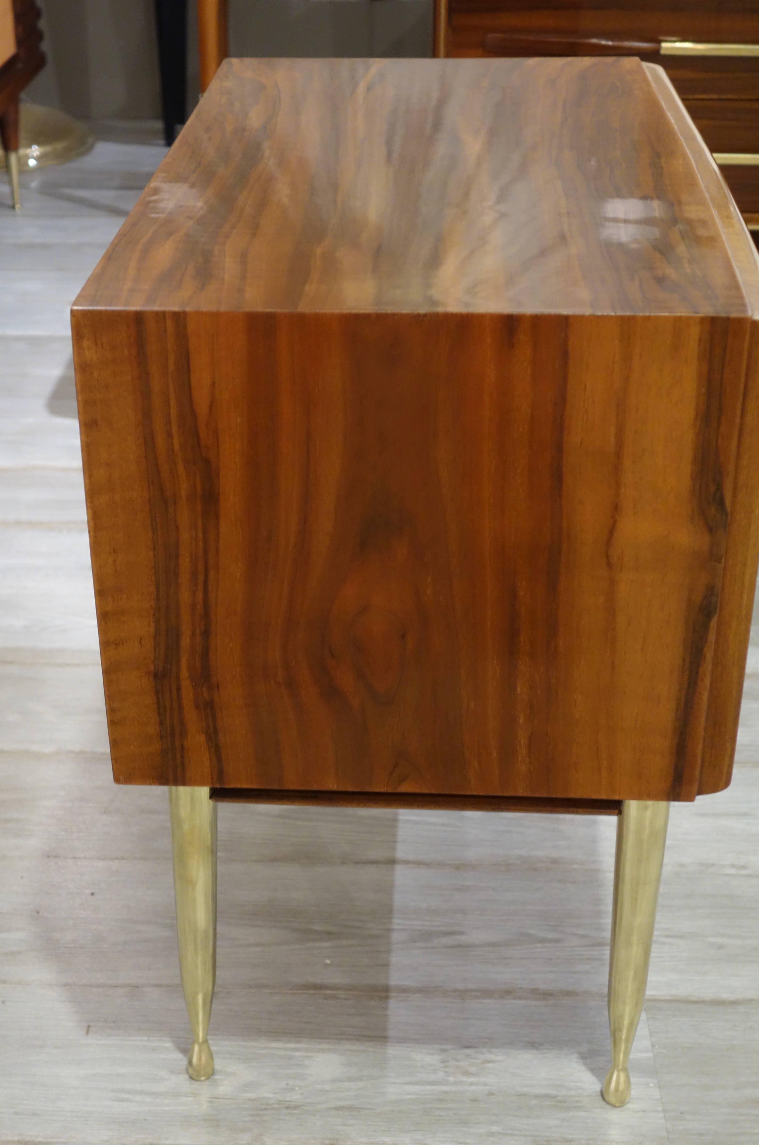 A pair of Mid-Century Italian fruitwood nightstands with two pull-out drawers with brass pulls and open lower bottom shelf resting on four brass tapered legs.