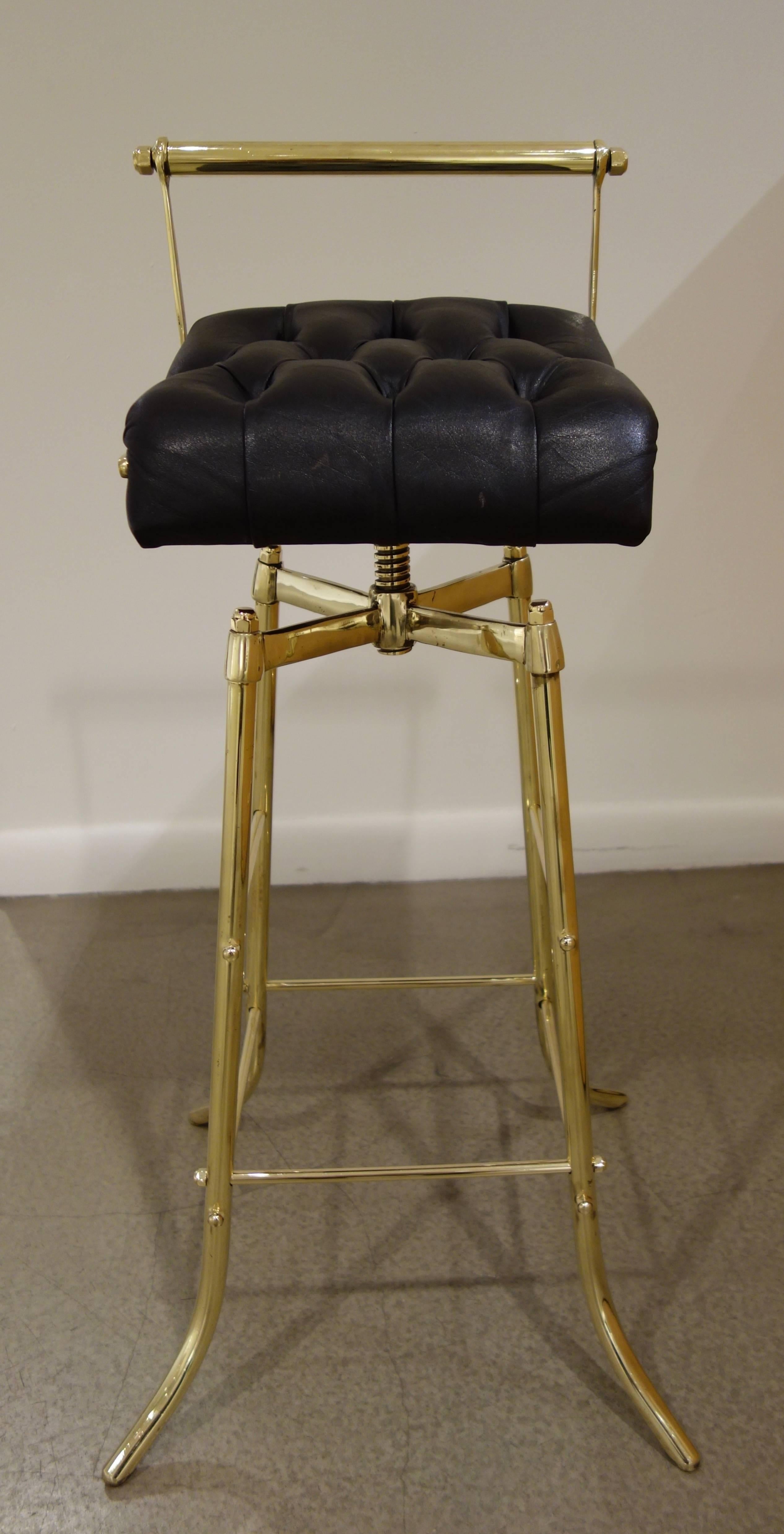A set of three circa 1970s Italian brass bar stools with original, tufted black leather upholstery, the revolving seats resting on professionally polished, adjustable brass bases.