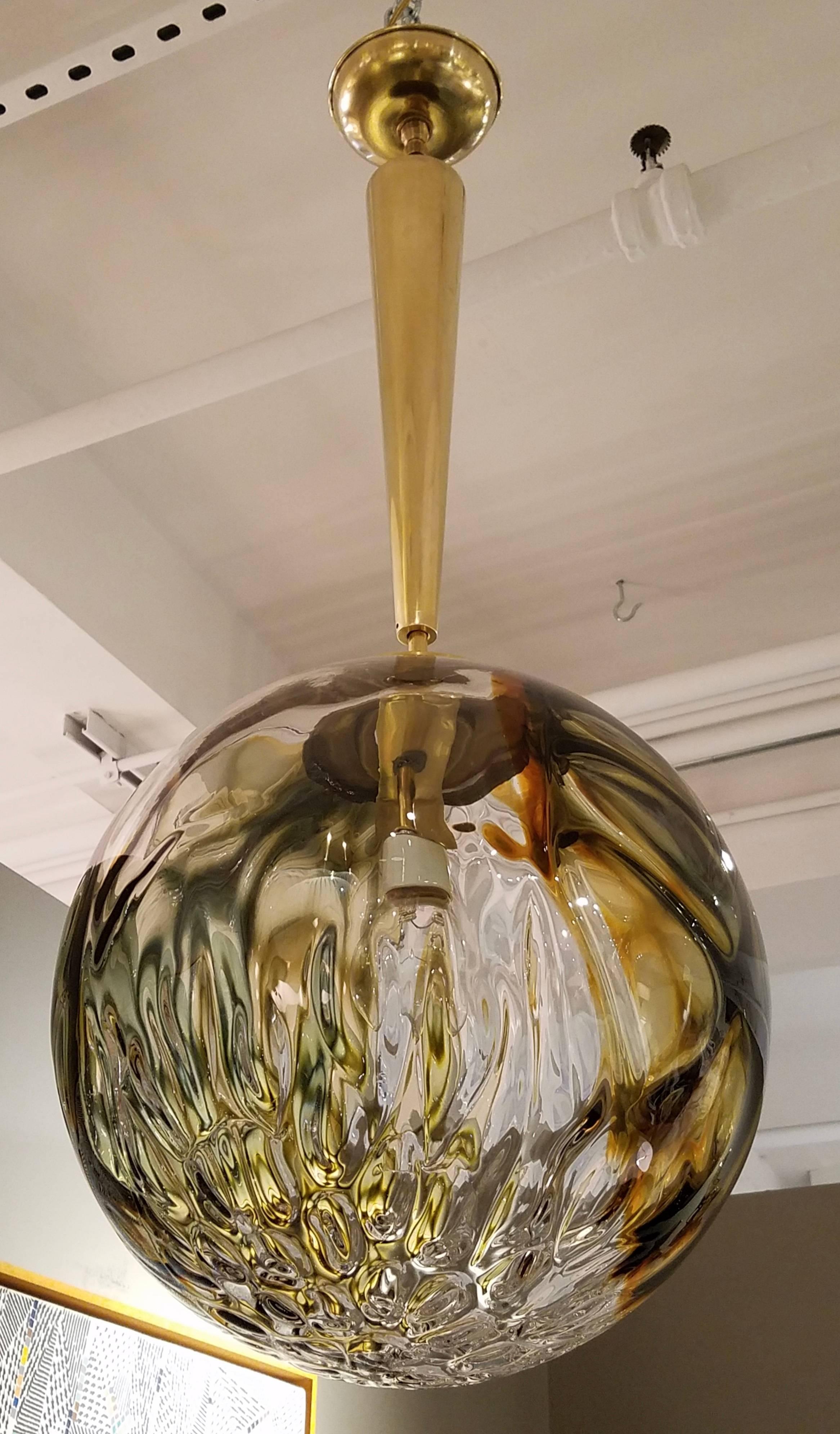 An Italian Mid-Century Murano globe with a mottled dark green, amber and clear coloration, the thick handblown glass with very unusual shallow lozenge shaped depressions creating textured, surface patterns of faceted prisms, the single socket newly