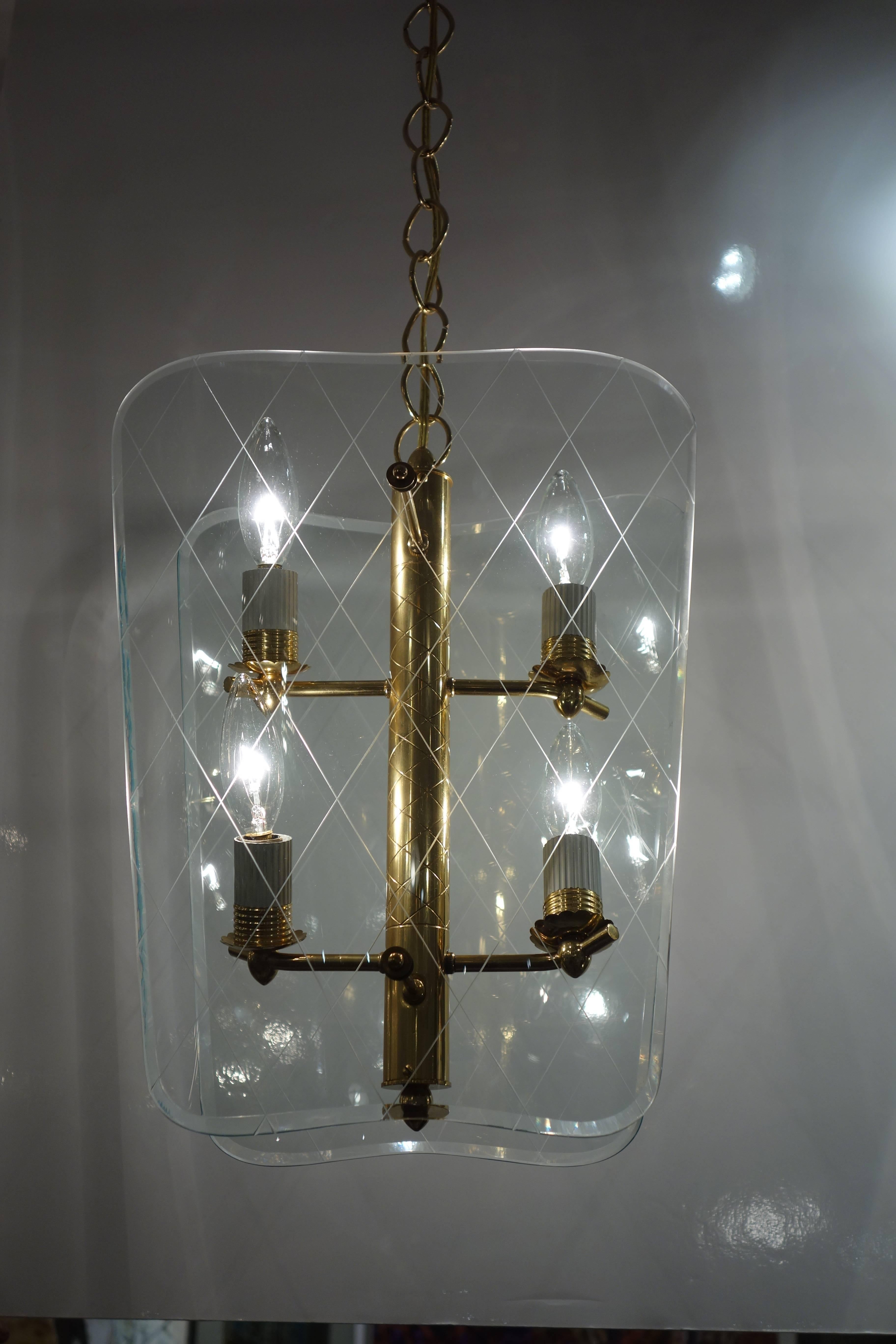 A Mid-Century lantern or chandelier in the style of Pietro Chiesa featuring a brass columnar pole with four newly wired chandelier light sockets attached to two shaped pieces of bevelled glass etched cross-hatching suspended by a brass chain and