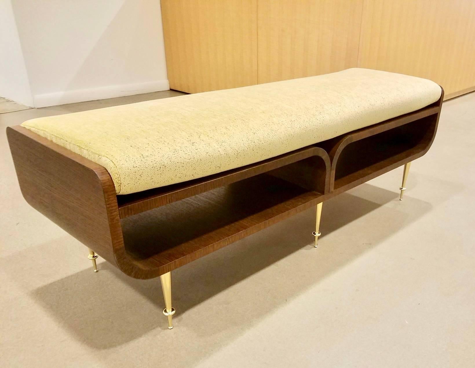 A limited edition contemporary studio made Italian bench of brown oak veneer with upturned sides with two tiers, the top with a removable pale mustard and brown flecked chenille cushion, the lower tier with two openings with central partition