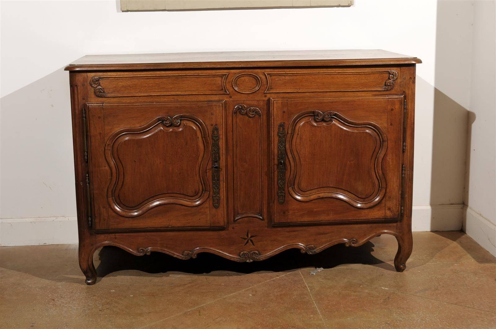 A French mid 18th century Louis XV period Provençal walnut buffet with its original hardware. This French buffet was born in the Southern region of Provence in the 1750s. This piece features a slightly raised rectangular top with rounded edges over