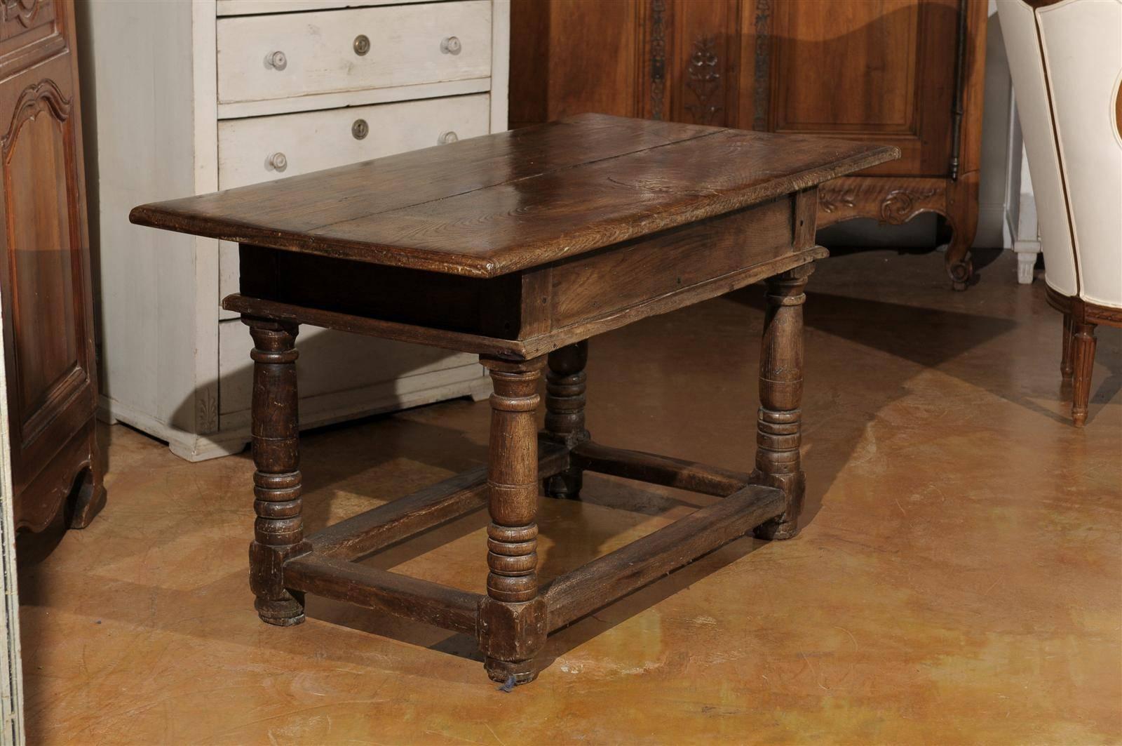 A French mid 18th century walnut library table of the Louis XV period with two drawers and original hardware. Born during the reign of King Louis XV, this French walnut table offers a stark contrast with the Rococo silhouettes typical of the era.