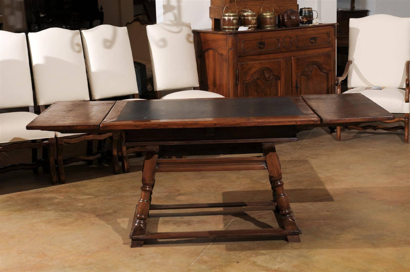 A Swiss wooden draw-leaf extension table with inset slate top, single side drawer and turned base from the early 19th century. This extension table was born in Switzerland in the early years of the 19th century. The rectangular top is adorned with