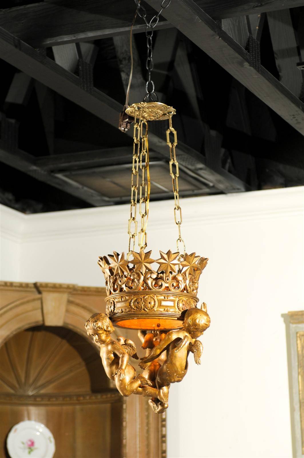 Swedish 19th century gilded wood chandelier with three cherubs supporting a gilded pierced crown.