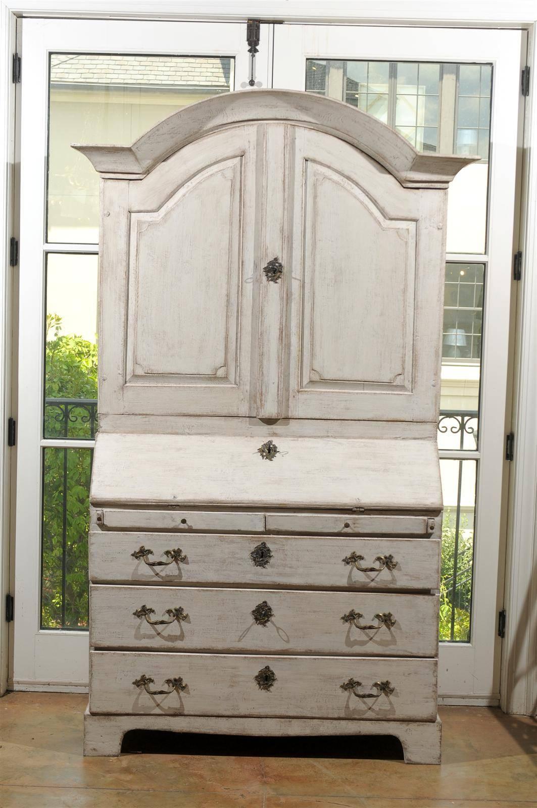 A Swedish painted wood Baroque style secretary with bonnet top, upper cabinet, slant-front desk, and lower drawers from the mid 19th century. This Swedish tall secretary features a bonnet-shaped beveled pediment, overhanging an upper cabinet made of