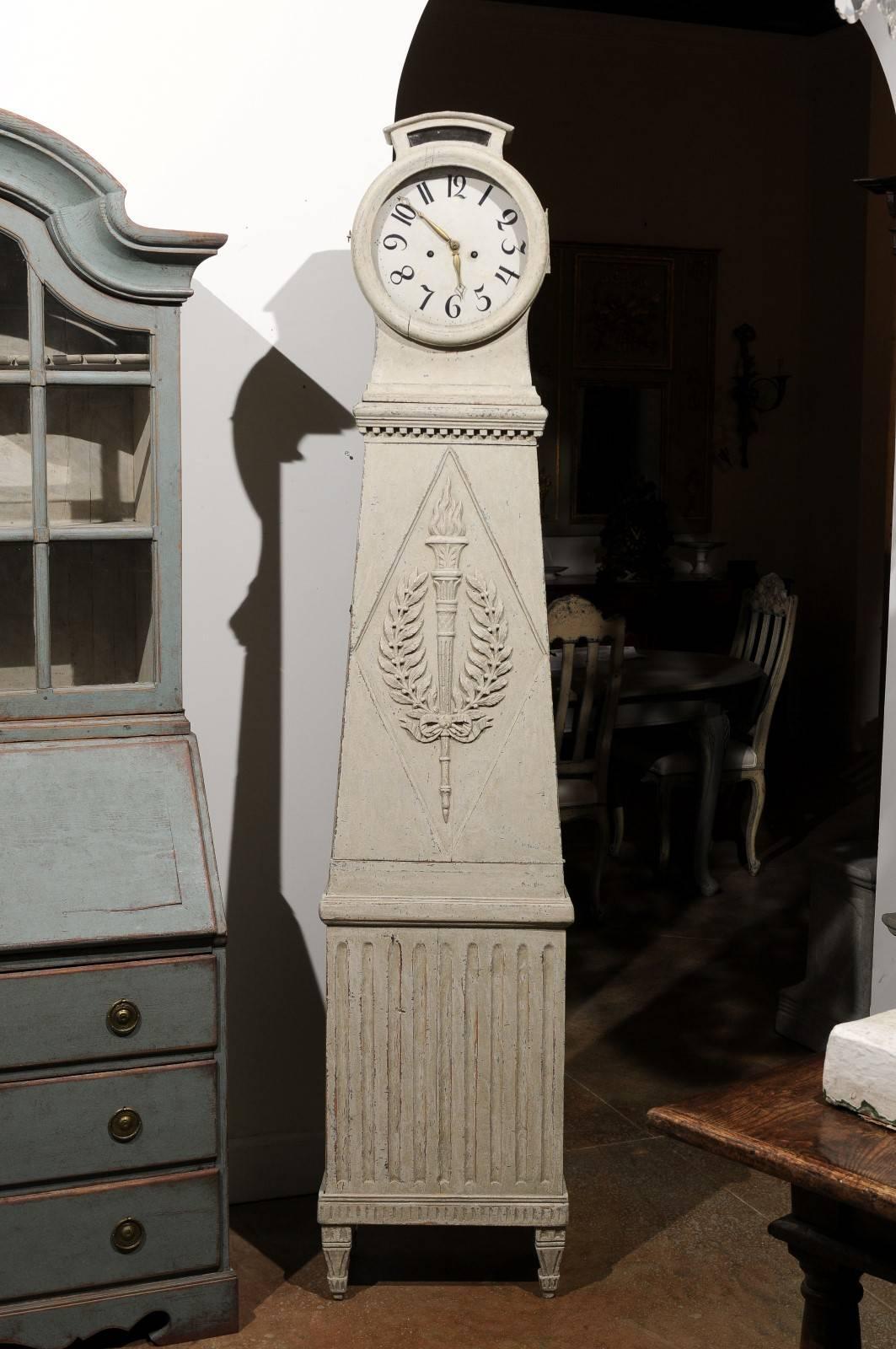 A Swedish Neoclassical style painted tall case clock from the mid 19th century, with original face and mechanisms. Featuring a face that is typical of what are commonly referred to as Mora clocks, this Swedish piece is topped with a delicately