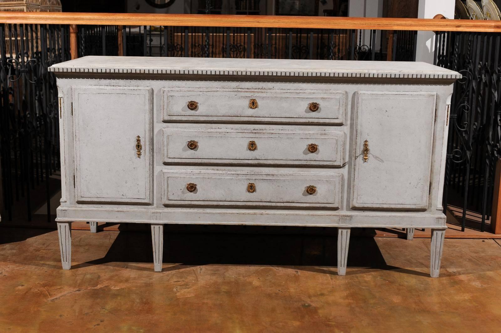 Swedish 19th century painted sideboard with three centre drawers flanked by single door cabinets raised on carved tapered legs.