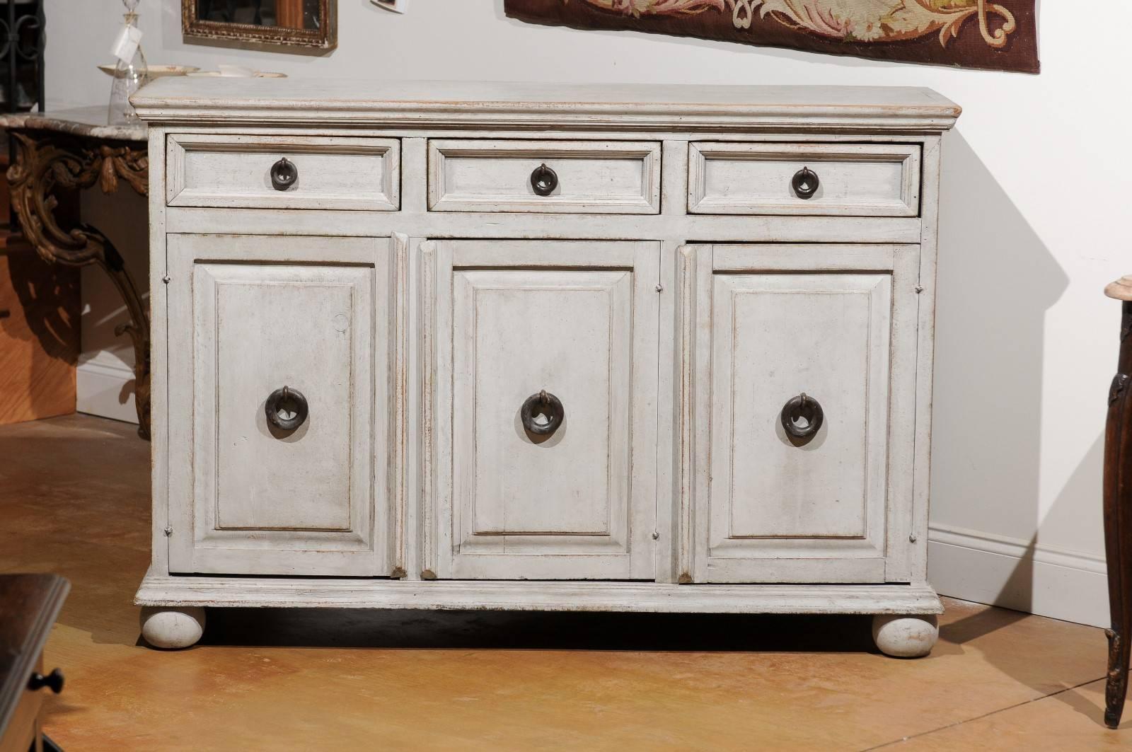 A Swedish painted wood enfilade with three drawers over three doors from the late 19th century. This Swedish long buffet features a rectangular molded top surmounting three drawers with recessed panels and circular ring pulls. Three doors located