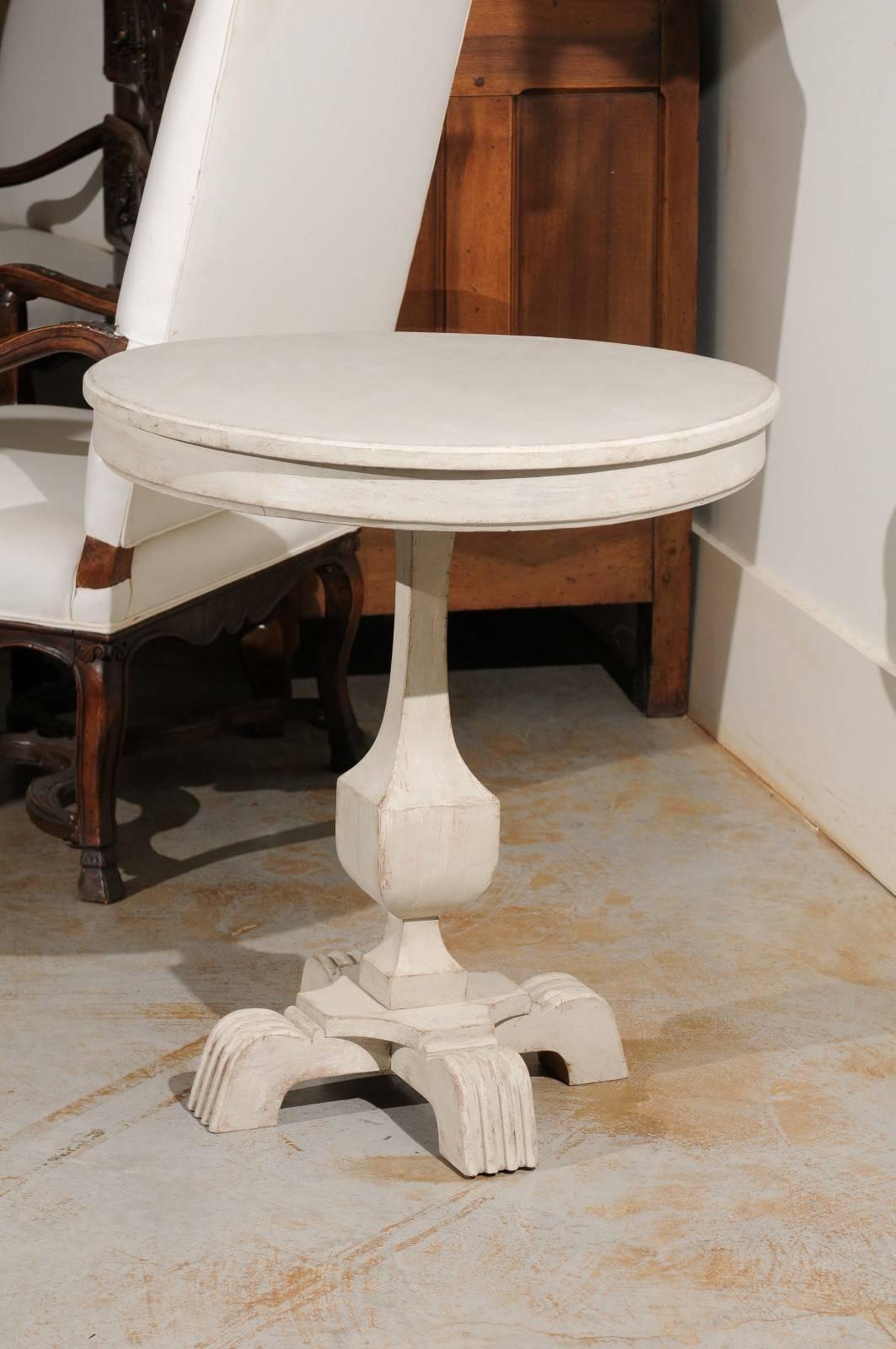 A Swedish painted wood guéridon table with carved feet from the late 19th century. This Swedish pedestal table features a circular top sitting above a simple apron. Elegantly raised on a pedestal base, the table rests on four unusual carved feet,