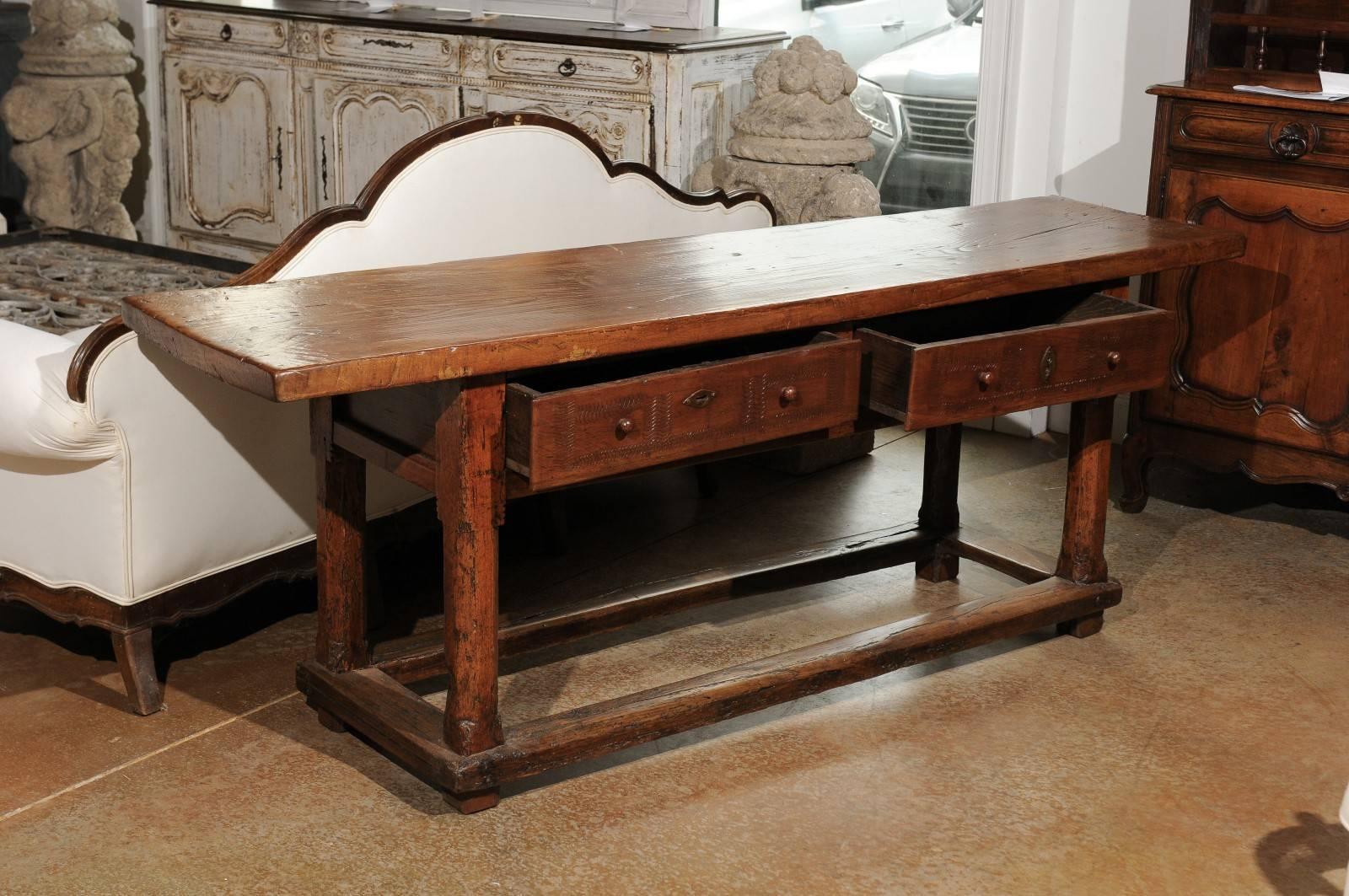 A French cherry sofa table with two drawers and side stretcher from the mid 17th century. Born in the early years of King Louis XIV's reign, this French sofa table features a rectangular single plank top sitting above two drawers with wavy 