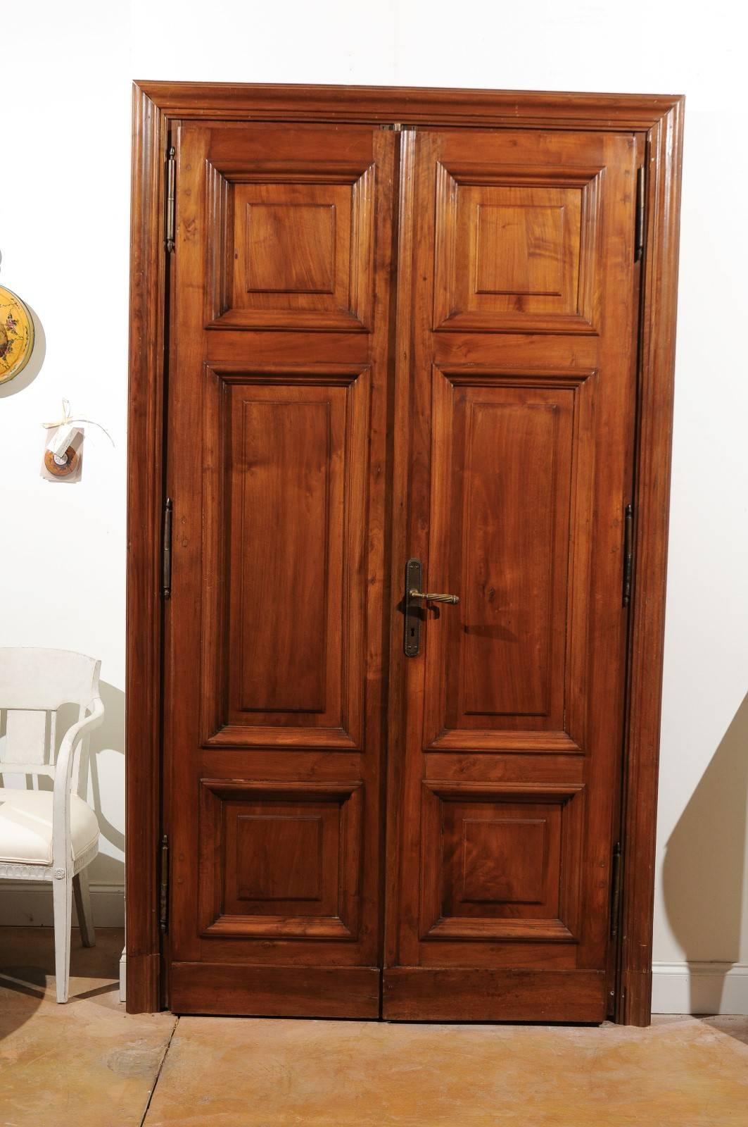 A pair of Italian walnut paneled double doors from the second half of the 19th century with original bronze hardware and keys and custom surround. Each of this pair of Italian double doors features some of the most beautiful European walnut we have