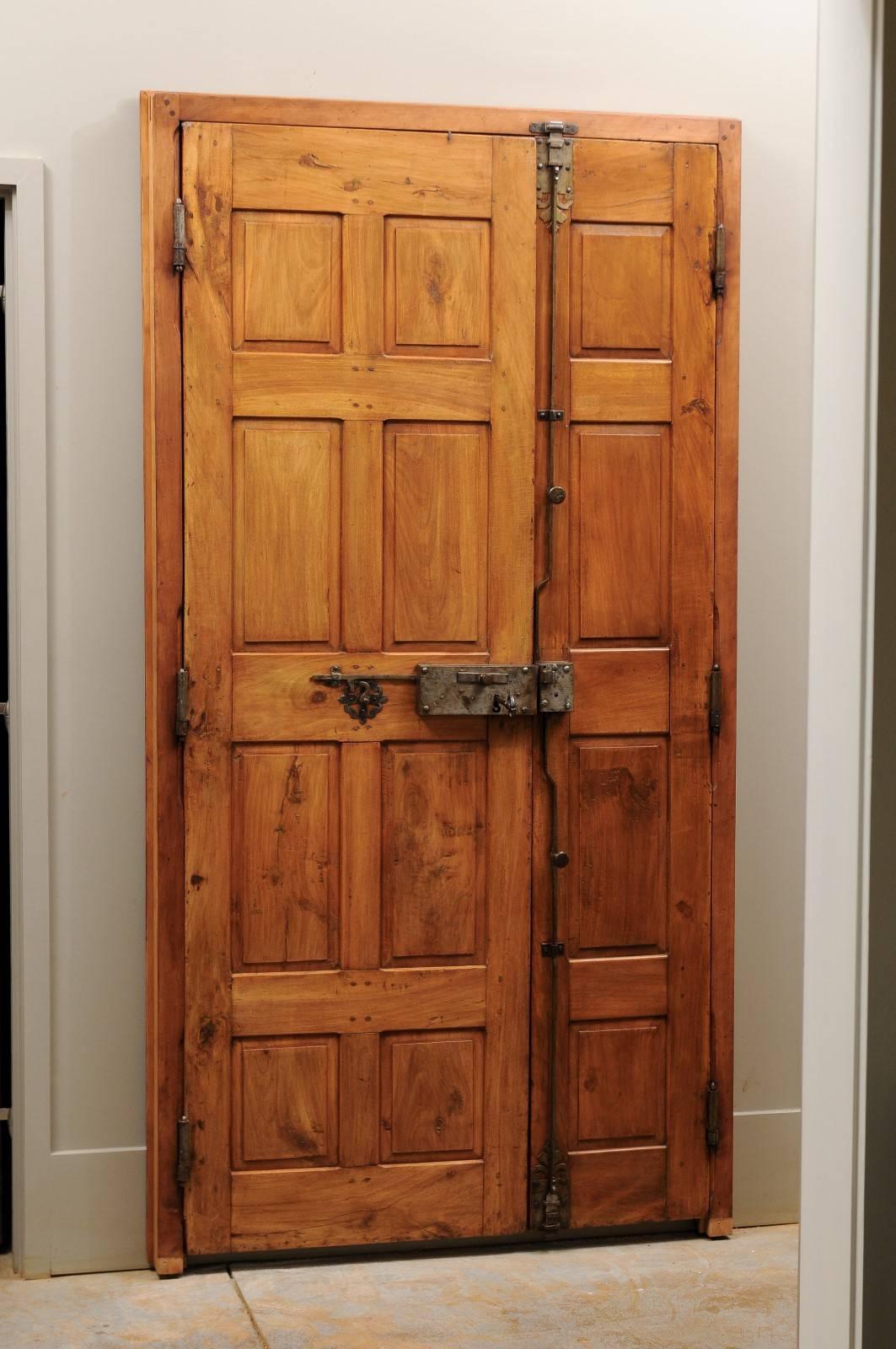 A French 18th century wooden door with custom door frame and original hardware. This elegant French carved wood door features two panels adorned with simple alternating raised square and rectangular motifs. The door retains its original hardware