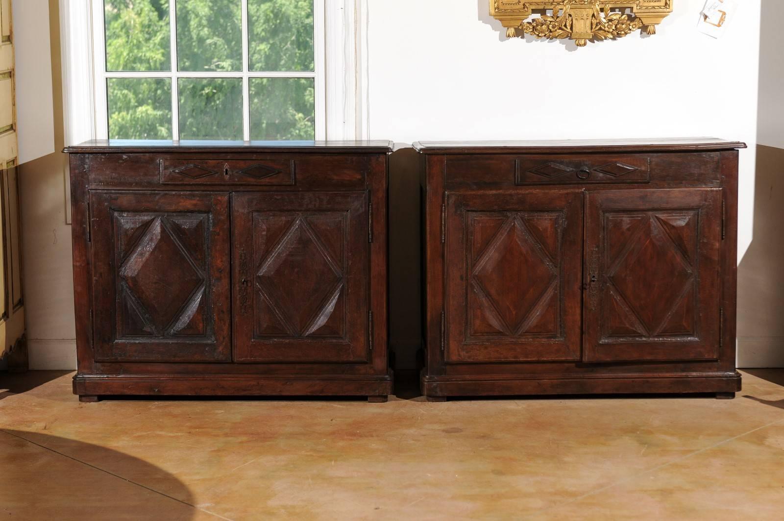 A pair of French walnut buffets from the 18th century with diamond pattern motifs on the doors. Each of this pair of French 18th century buffets features a rectangular top with rounded edge over a central single hand-cut dovetailed drawer. Two doors