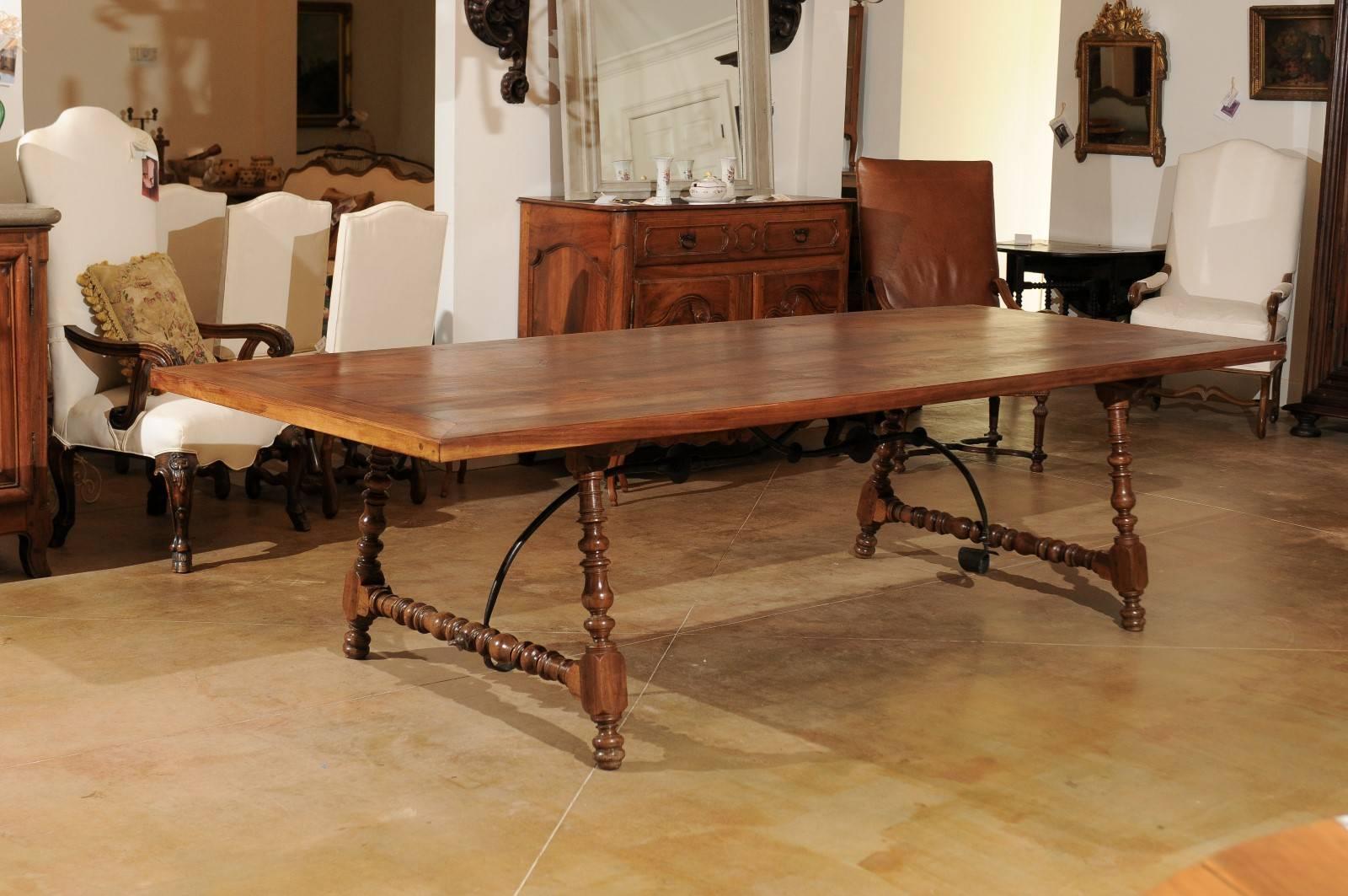 This exquisite Spanish Fratino table from the 18th century is made of walnut and features a long rectangular top over a beautifully turned base. Each side shows slightly splayed legs, connected two by two with a side stretcher. A hand-forged iron
