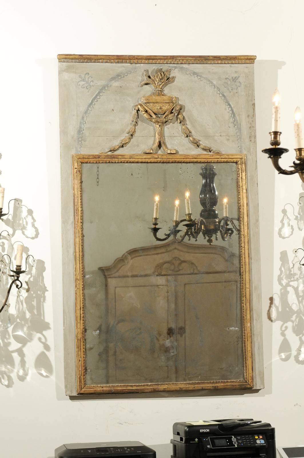 A French neoclassical trumeau mirror with pot-à-feu giltwood motif and mercury glass from the late 18th-early 19th century. This French painted trumeau mirror features a linear profile accented with painted and gilded accents. A dentil molding at