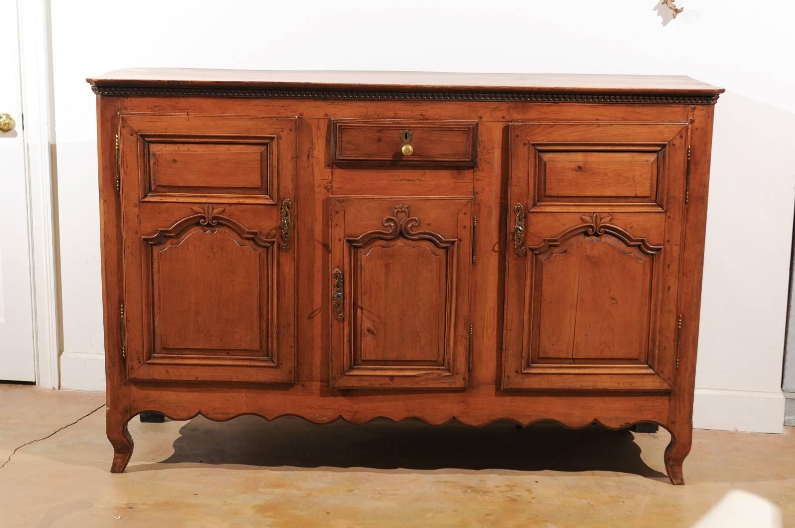 A French 18th century Louis XV cherry enfilade with single drawer over three doors. This French long buffet from the second half of the 18th century features a rectangular three-plank top with canted corners over a delicate rais-de-coeur frieze