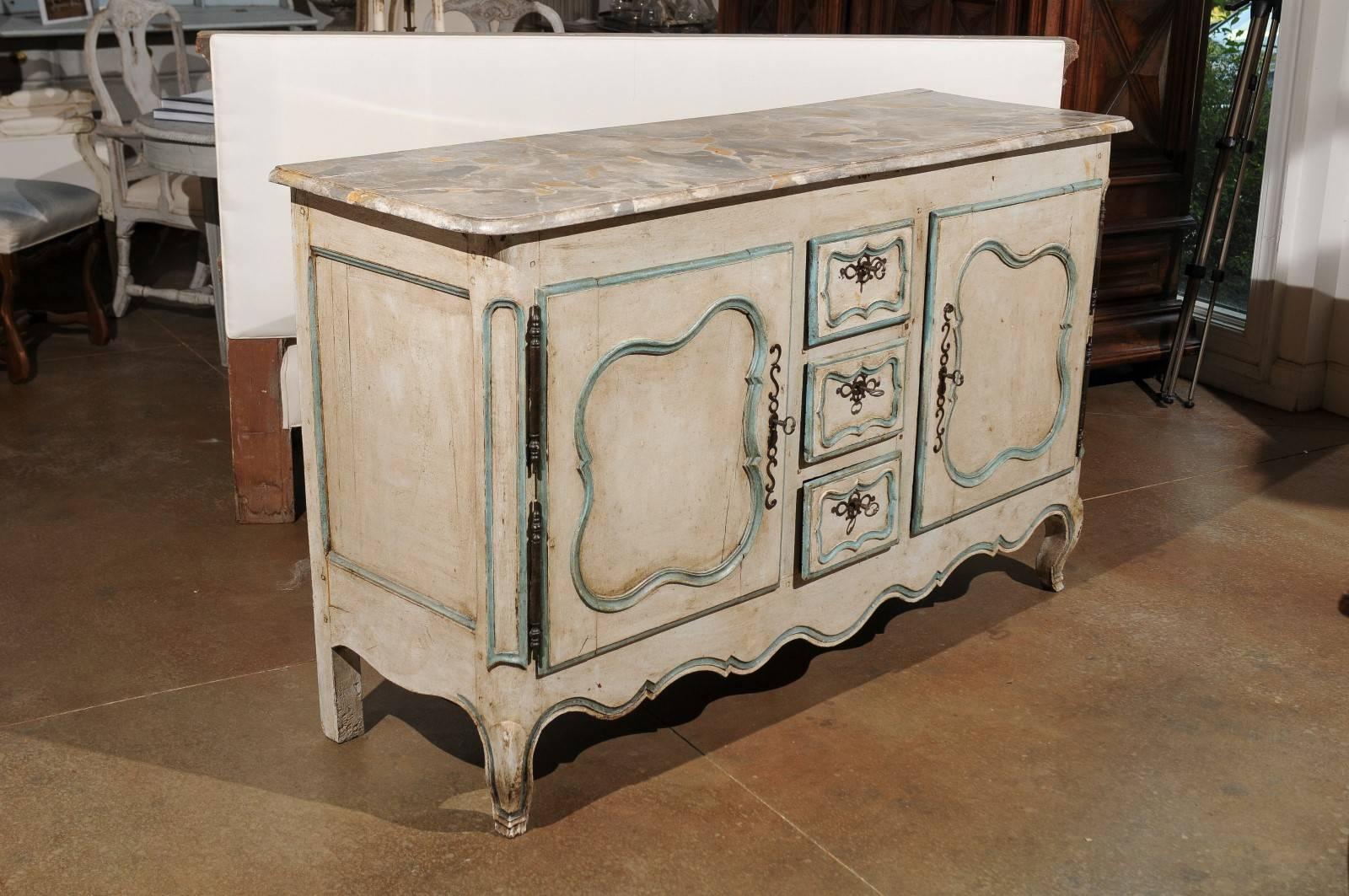 A French Louis XV period painted wood buffet with marbleized top, two doors and three drawers from the mid-18th century. This French buffet features a rectangular faux-marble top with rounded edges overhanging two carved doors flanking three small