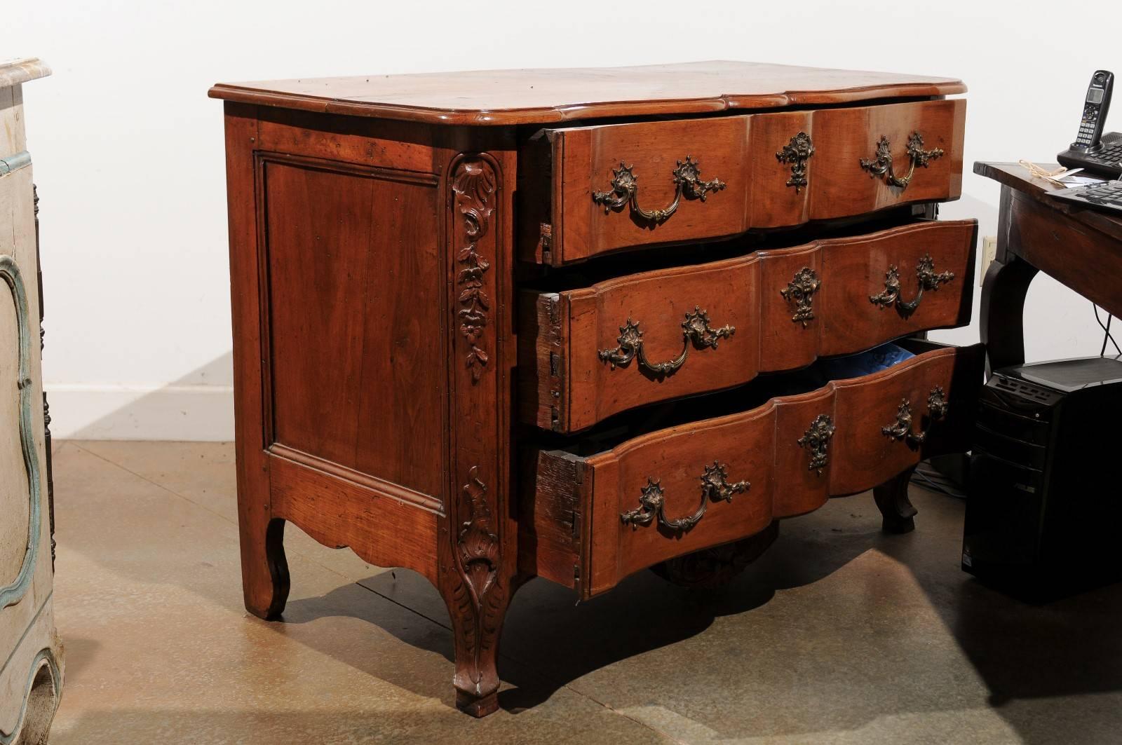 A French Regence walnut three-drawer commode en arbalete made in the manner of Thomas and Pierre Hache, ébénistes from Grenoble. This French Regence commode features a crossbow front, surmounted by a shaped two-plank top. The three hand-cut