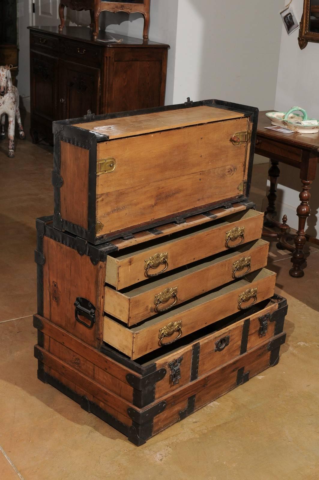 An English antique wooden steamer trunk with iron banding and multiple compartments from the 20th century. This English steamer trunk features a linear wooden body, reinforced with exceptional iron banding. The trunk ingeniously opens via a brass