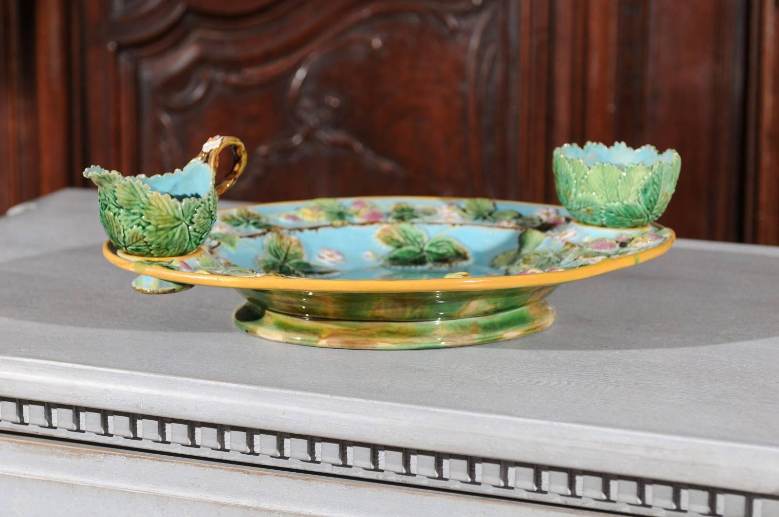 An English majolica strawberry dish set made of an oval plate with its cream jug and sugar bowl made by George Jones & Sons ceramists in the second half of the 19th century. Created circa 1875, this strawberry dish features a turquoise background