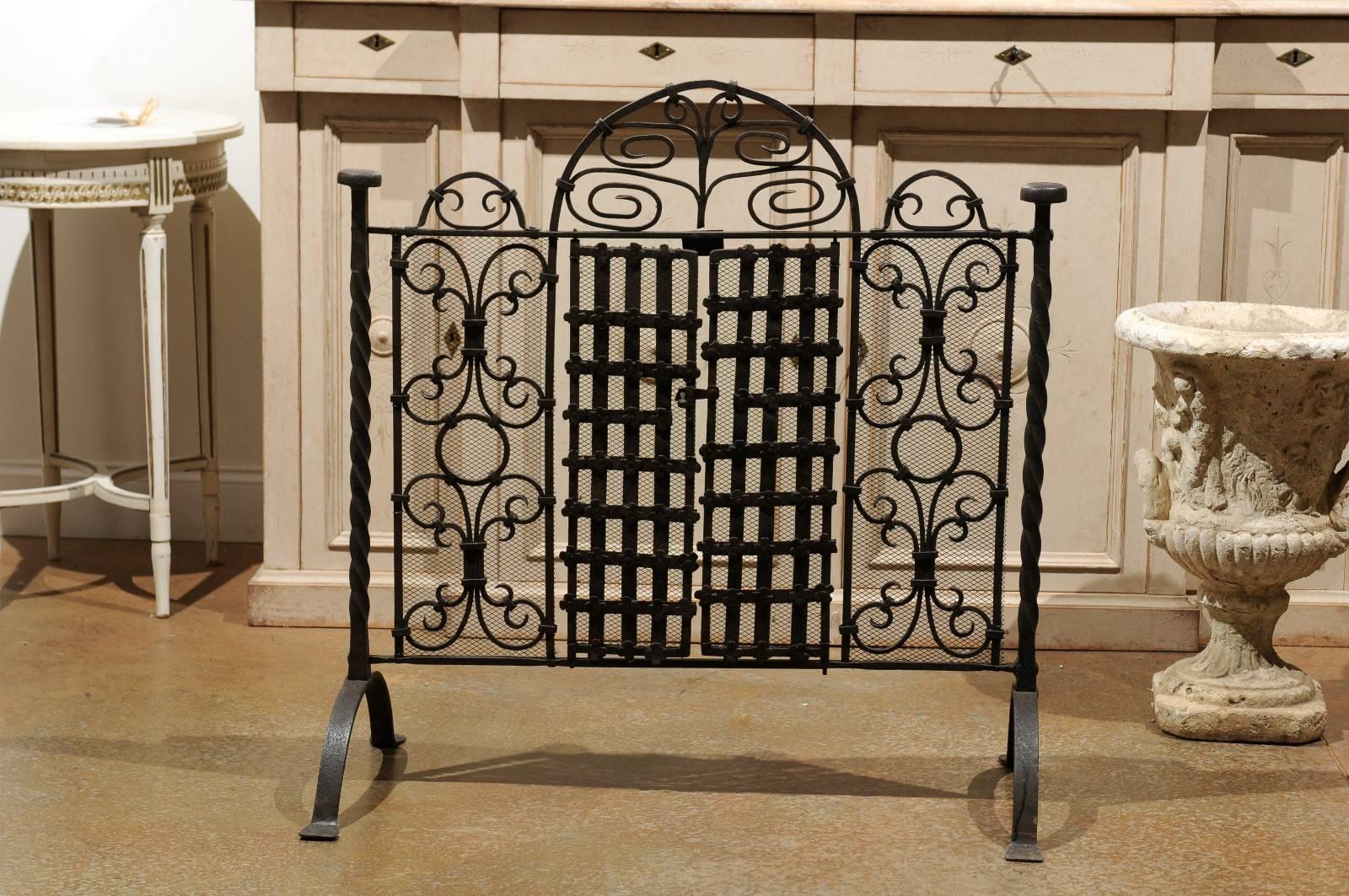 A French wrought iron freestanding firescreen with two central operational doors from the 19th century. This French firescreen features a wrought iron armature made of two lateral twisted supports. Our attention is immediately drawn to the central