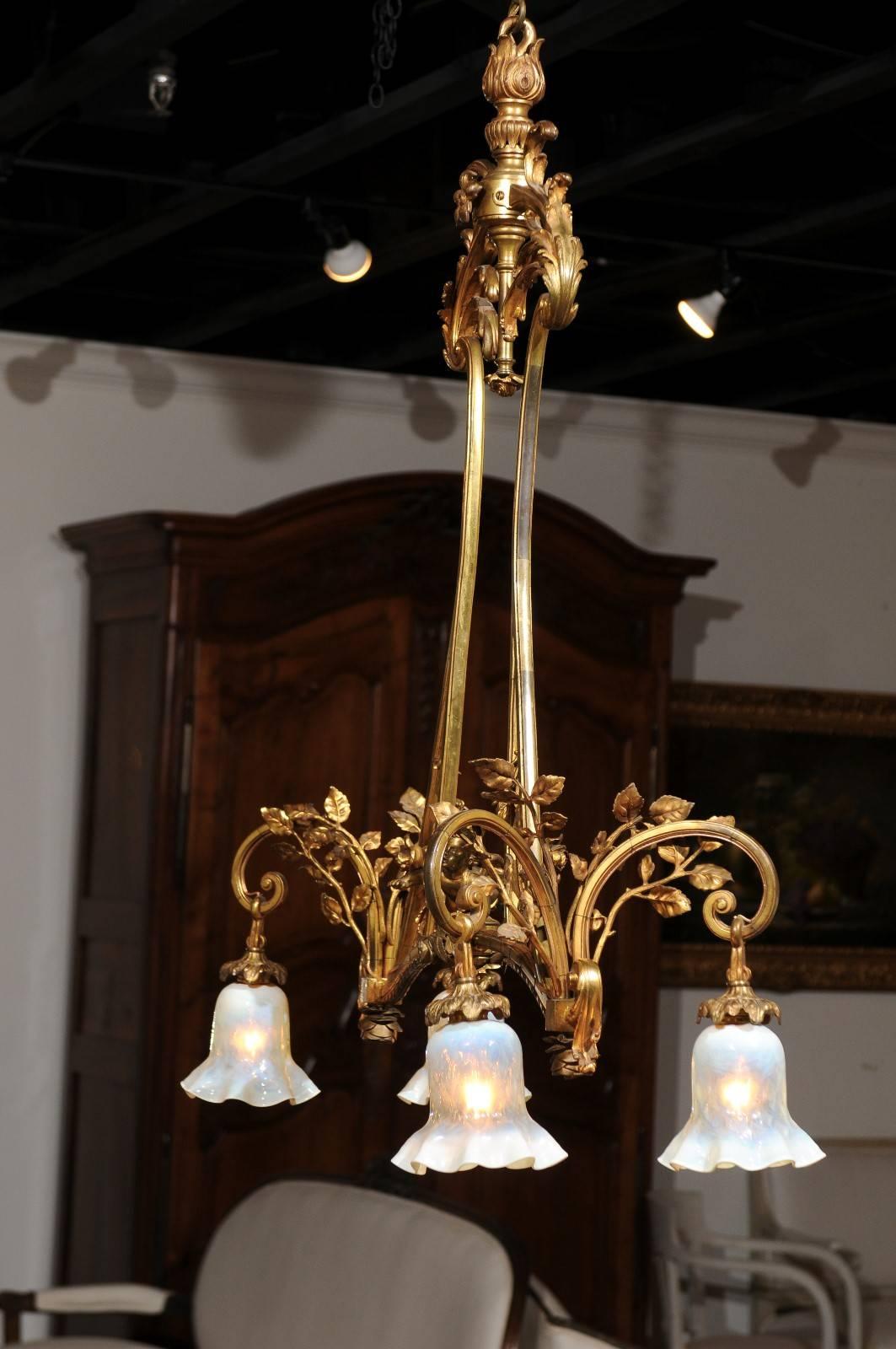 A French ormolu four-light chandelier with mounted cherub, vines, leaves and cloches shades from the 19th century. This French gilt bronze chandelier features a central armature adorned with acanthus leaves at the top, leading the eye down to