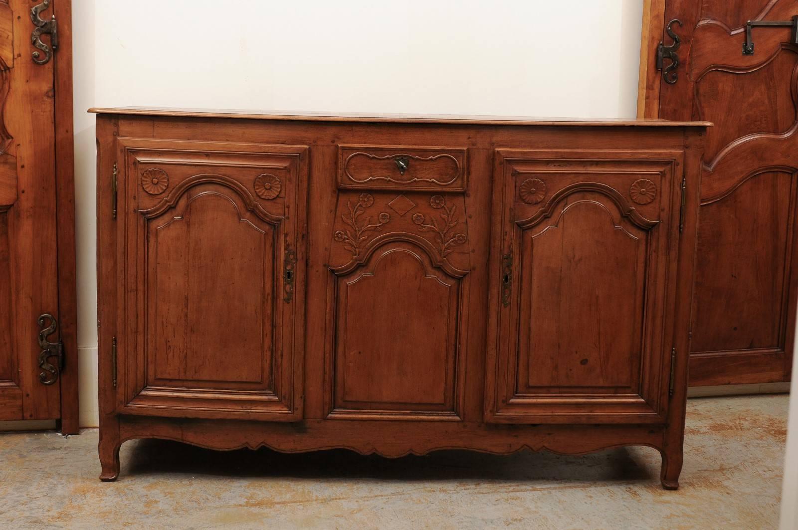 A French Louis XV style carved cherry enfilade from the Picardy region with single drawer and two doors from the late 18th century. This northern French long buffet features a rectangular planked top with rounded edges over a single drawer placed in