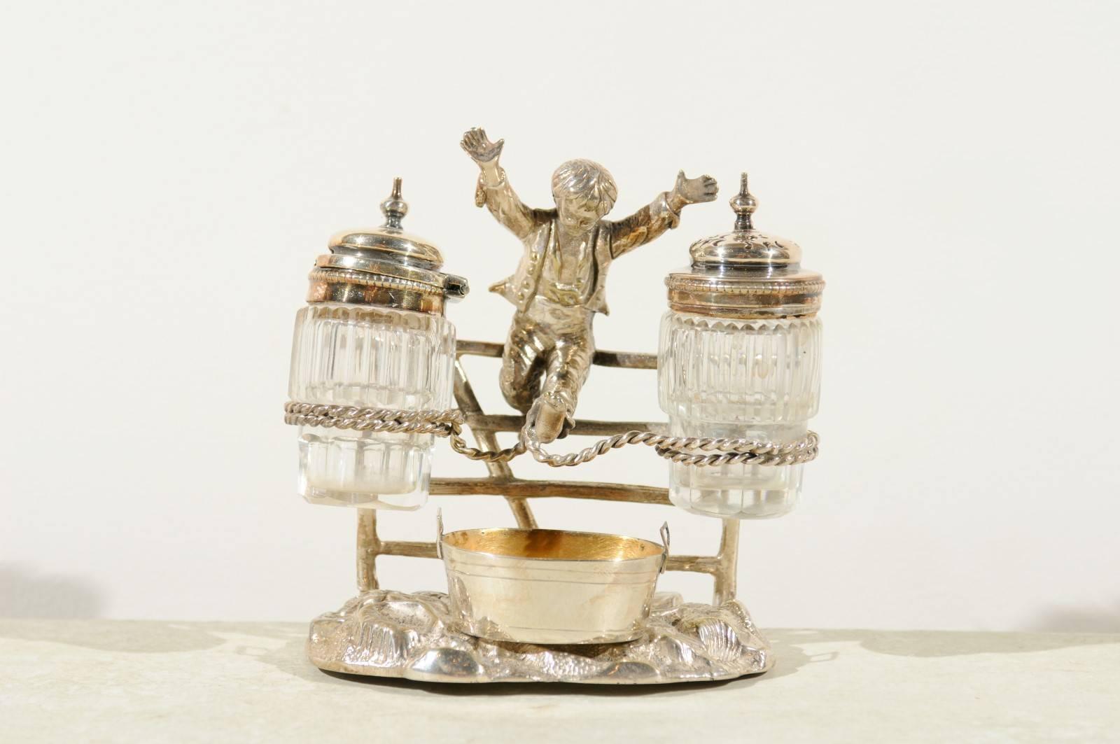 An English figurative silver plated cruet set, registered 1873 with young boy joyously jumping for joy. This charming late 19th century silver cruet set features an elegantly dressed young boy, his arms extended forward, caught in a mid-air jump, in