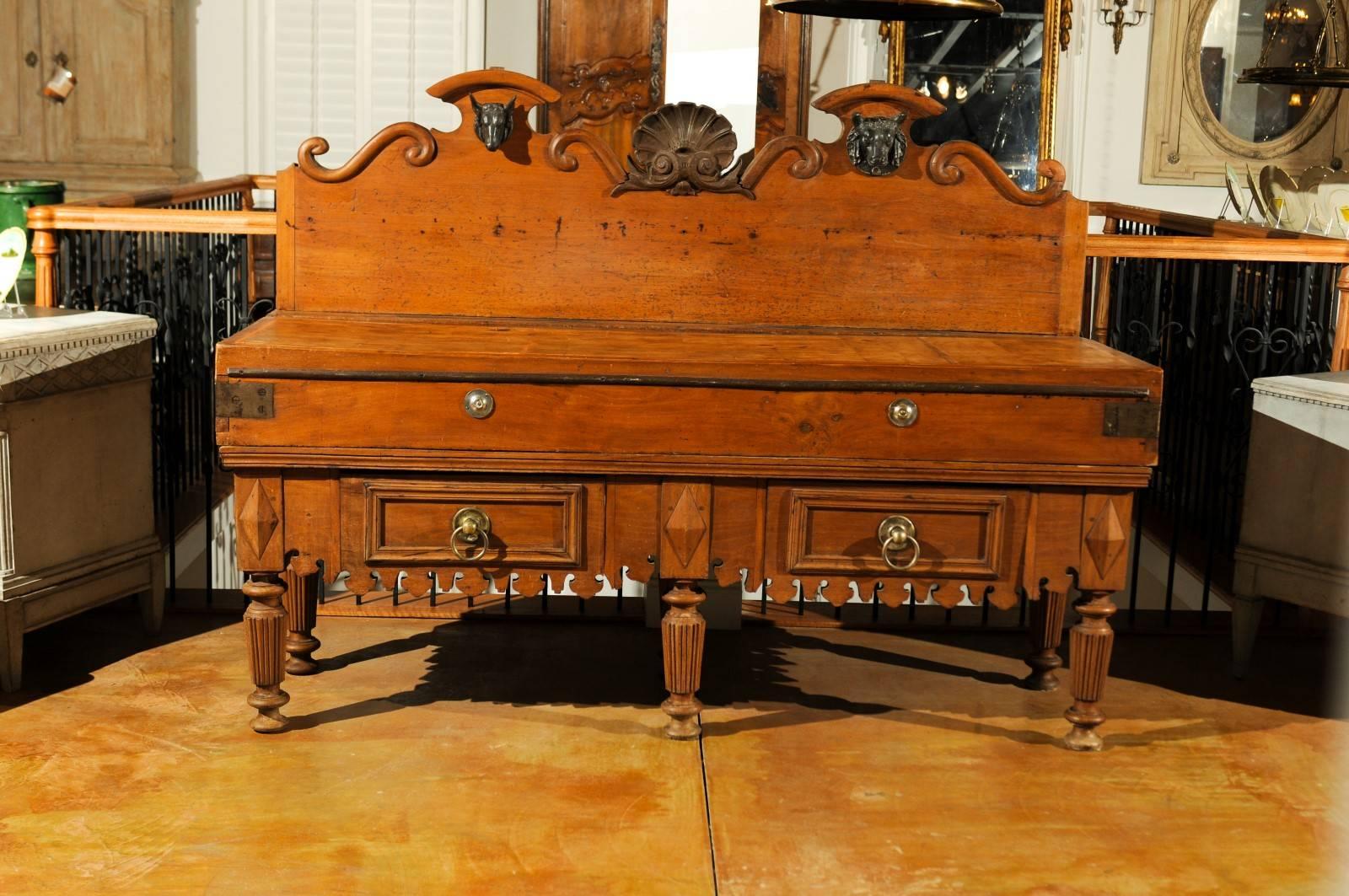 A French large-scale butcher's table with carved back, mounted steer heads and double knife slats from the late 19th century. This exquisite French butcher block features a nicely carved tall back, adorned in its central section with an iron shell,