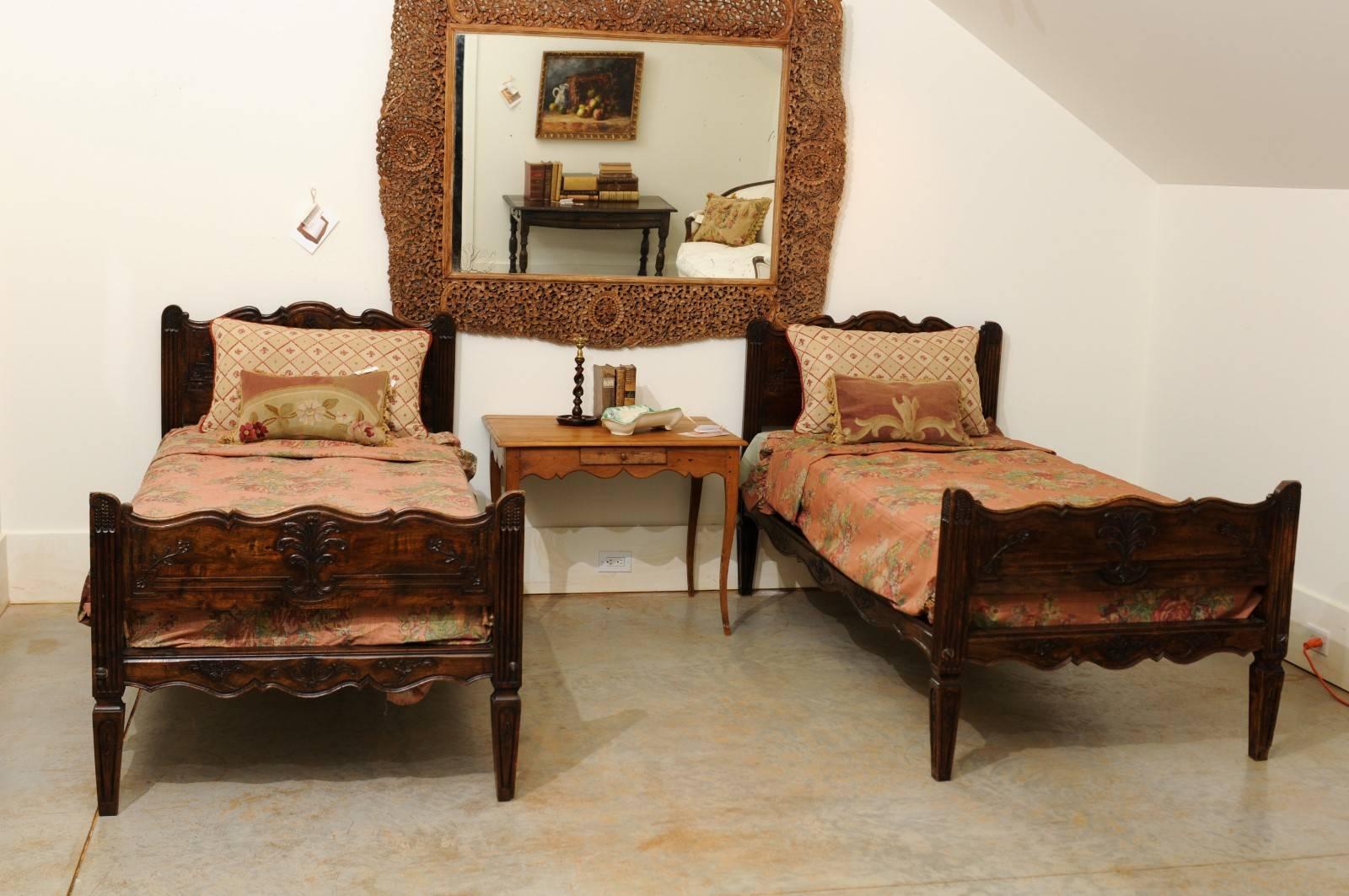 A pair of French carved walnut twin beds with floral motifs, sheaf of wheat and custom mattresses from the 19th century. Each of this pair of French wooden twin beds features an exquisitely carved headboard and footboard. The headboard is adorned