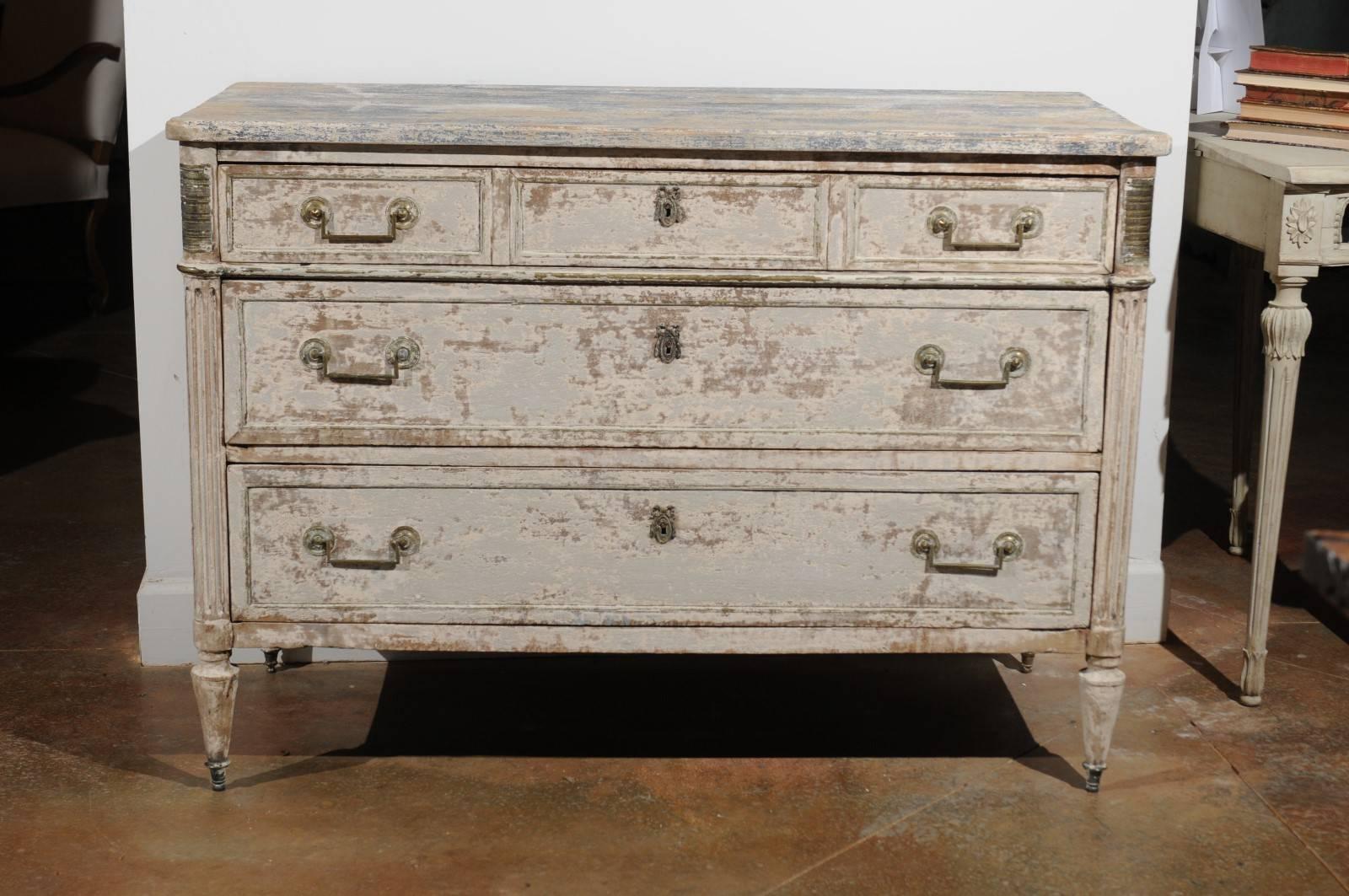 A French neoclassical period painted wood three-drawer commode from the early 19th century. This French commode features a rectangular top with rounded corners in the front, surmounting three drawers, a smaller one at the top over two larger ones.
