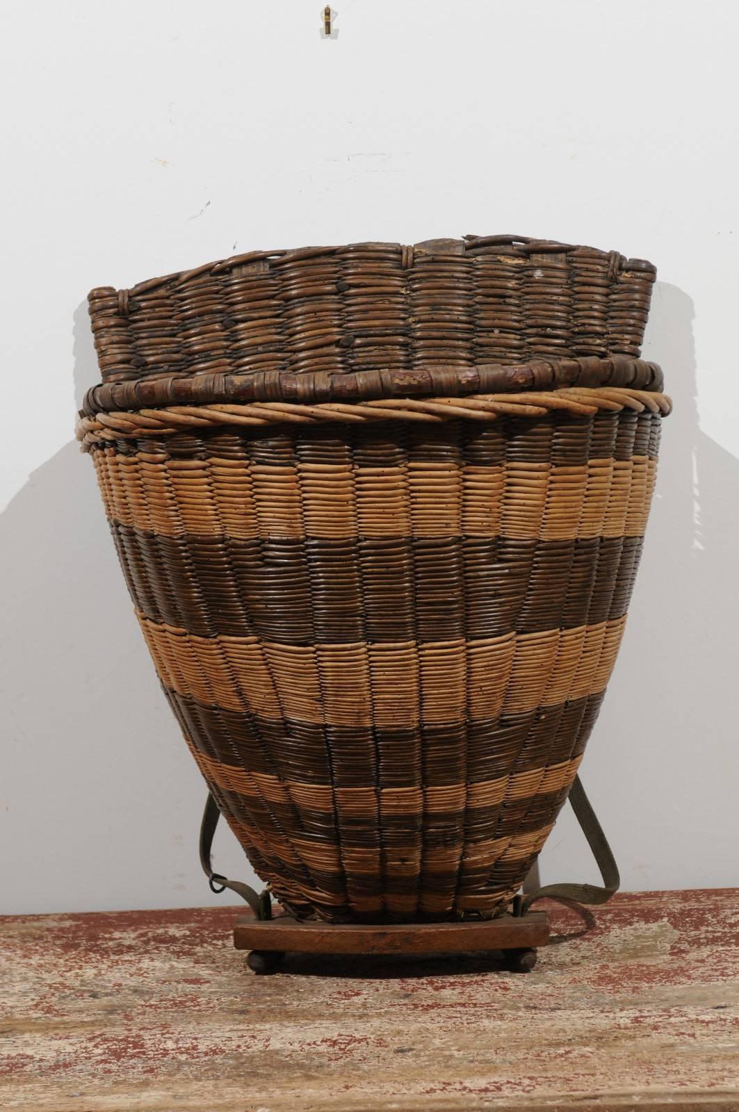 A French 19th century small wicker grape harvesting basket from the Burgundy town of Chablis. This two-toned harvesters basket features its two leather straps, used to help the workers carry it on their back and allowing them to pick up the grapes