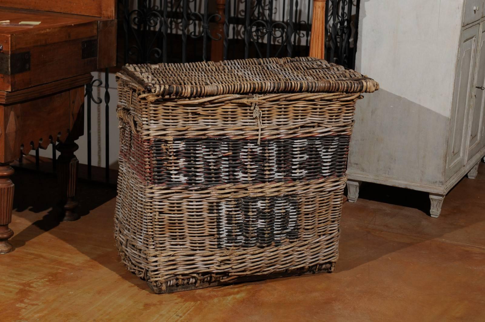A large English antique wicker hamper basket from the 19th century. This English linen basket features a lid that opens to reveal great storage possibilities, perhaps used as a hamper or toy basket. The lateral handles allow the piece to be moved