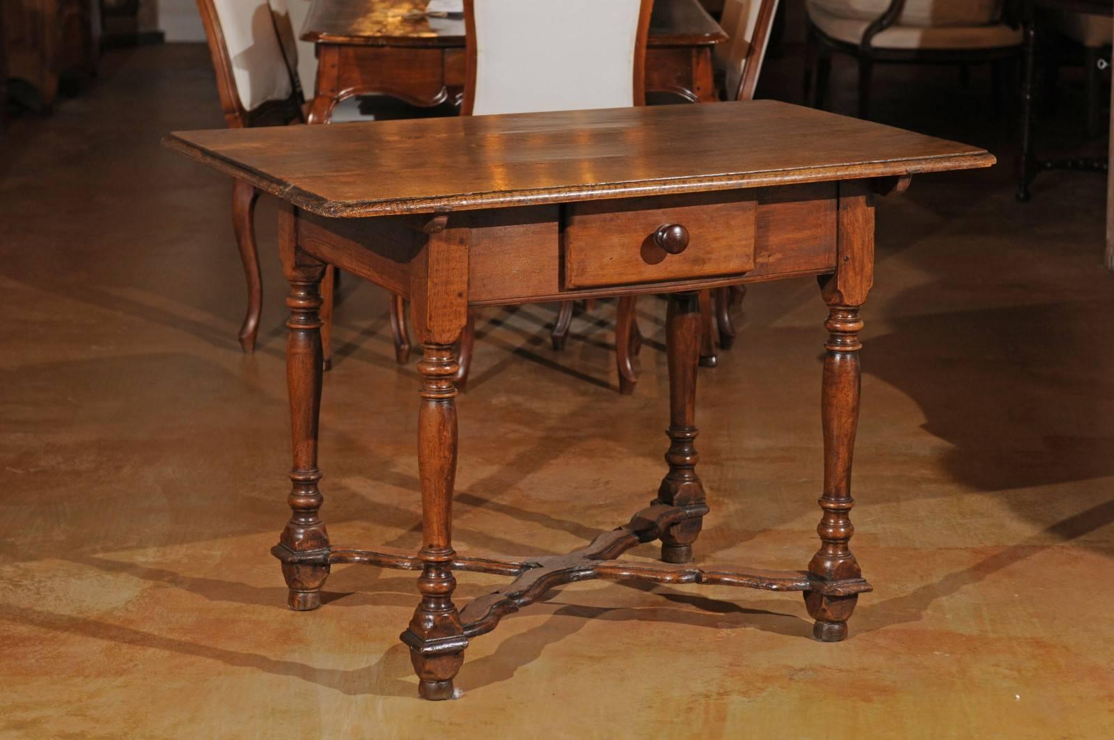 A French walnut side table with single drawer and Saint-Andrew cross stretcher from the late 18th century. Born during the last years of the Ancient Régime, this French side table features a rectangular planked top with bevelled edges, overhanging a