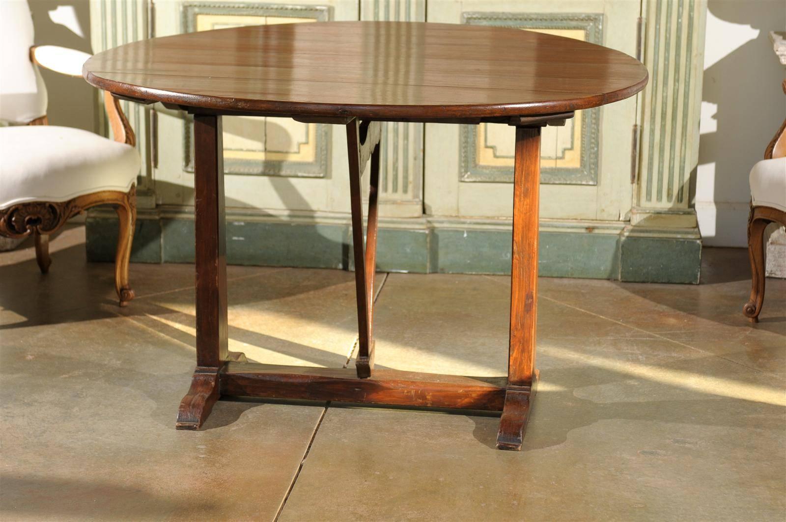 A French round heart of pine wine tasting table from the late 19th century. This French wine tasting table features a circular tilt-top raised on a trestle base with butterfly wedge, rotating to allow the top to tilt at will. Wine tasting tables are