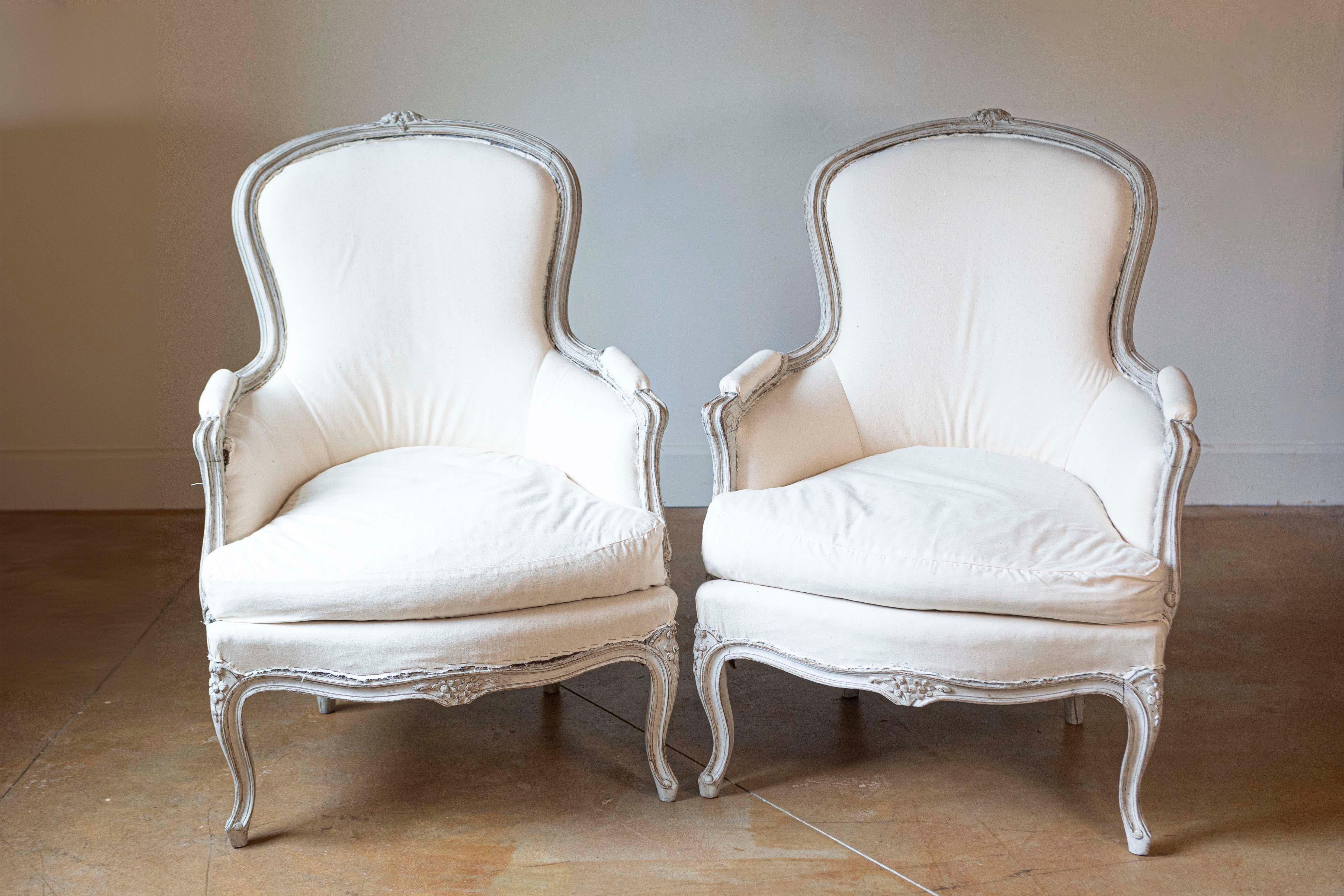 Pareja de sillas bergères clásicas de estilo rococó sueco, pintadas de gris claro, de hacia 1890, con decoración floral tallada, patas cabriolé y tapicería. Sumérgete en el poético encanto de este par de bergères suecas de estilo rococó, de hacia