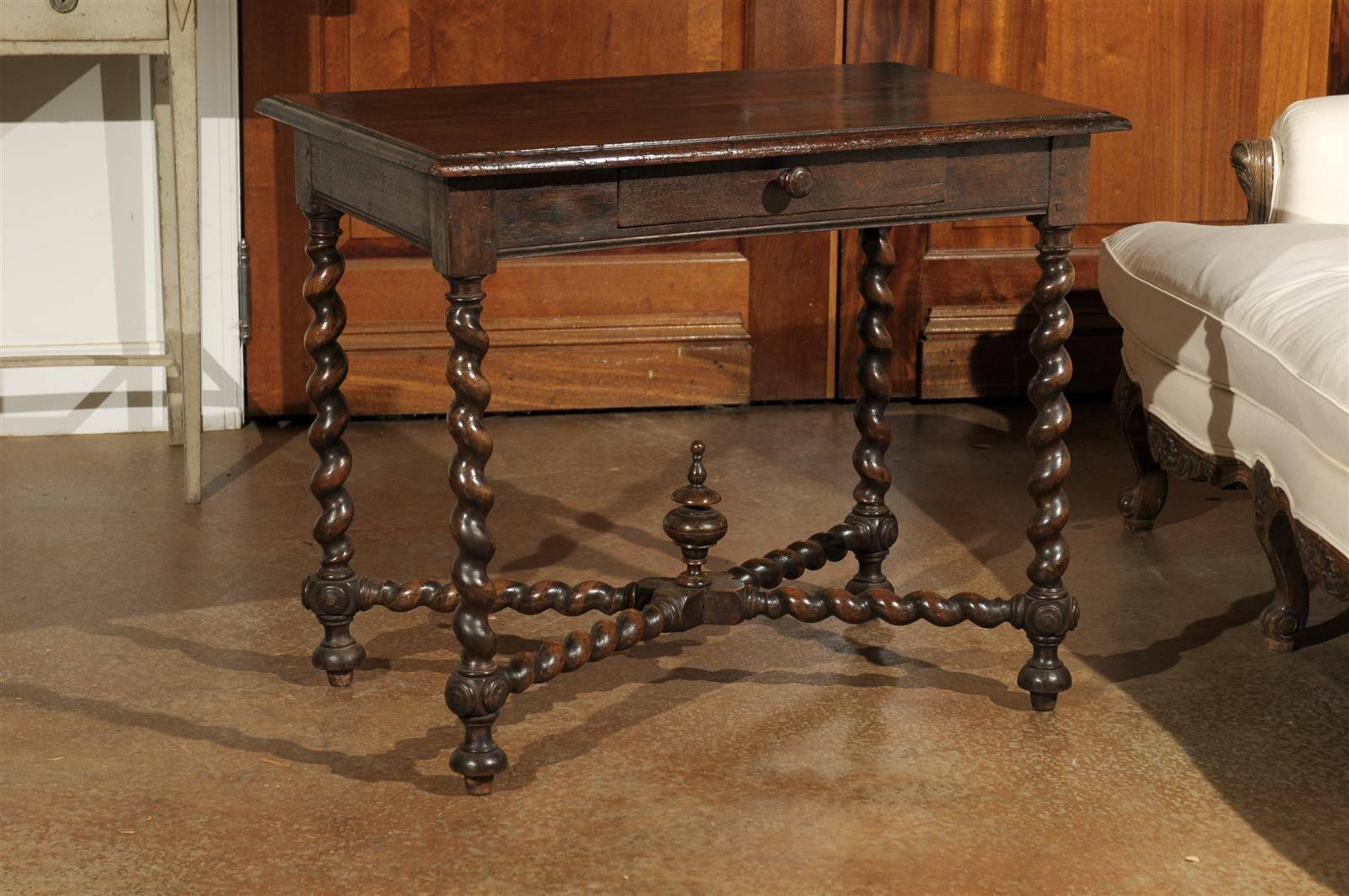 A mid 17th century French Louis XIII period walnut side table with single drawer, barley twist legs and carved cross stretcher. This French Louis XIII side table features a rectangular top with beveled edges, sitting above a single drawer with