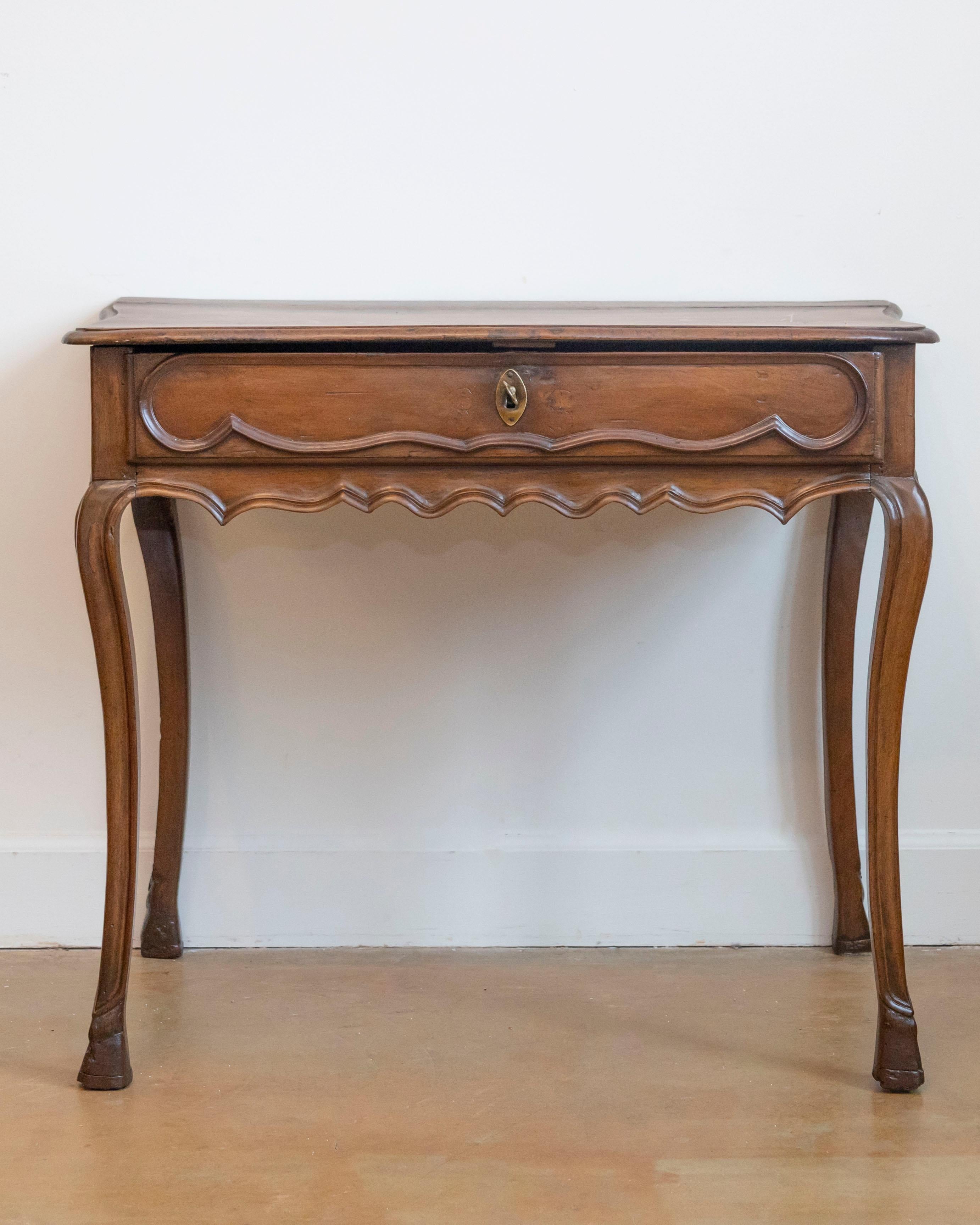 This 19th-century Italian Baroque-style console table showcases exquisite hand-carved walnut, featuring a gracefully serpentine-shaped top and elegant cabriole legs. The rich walnut wood displays a warm patina, highlighting the natural grain and