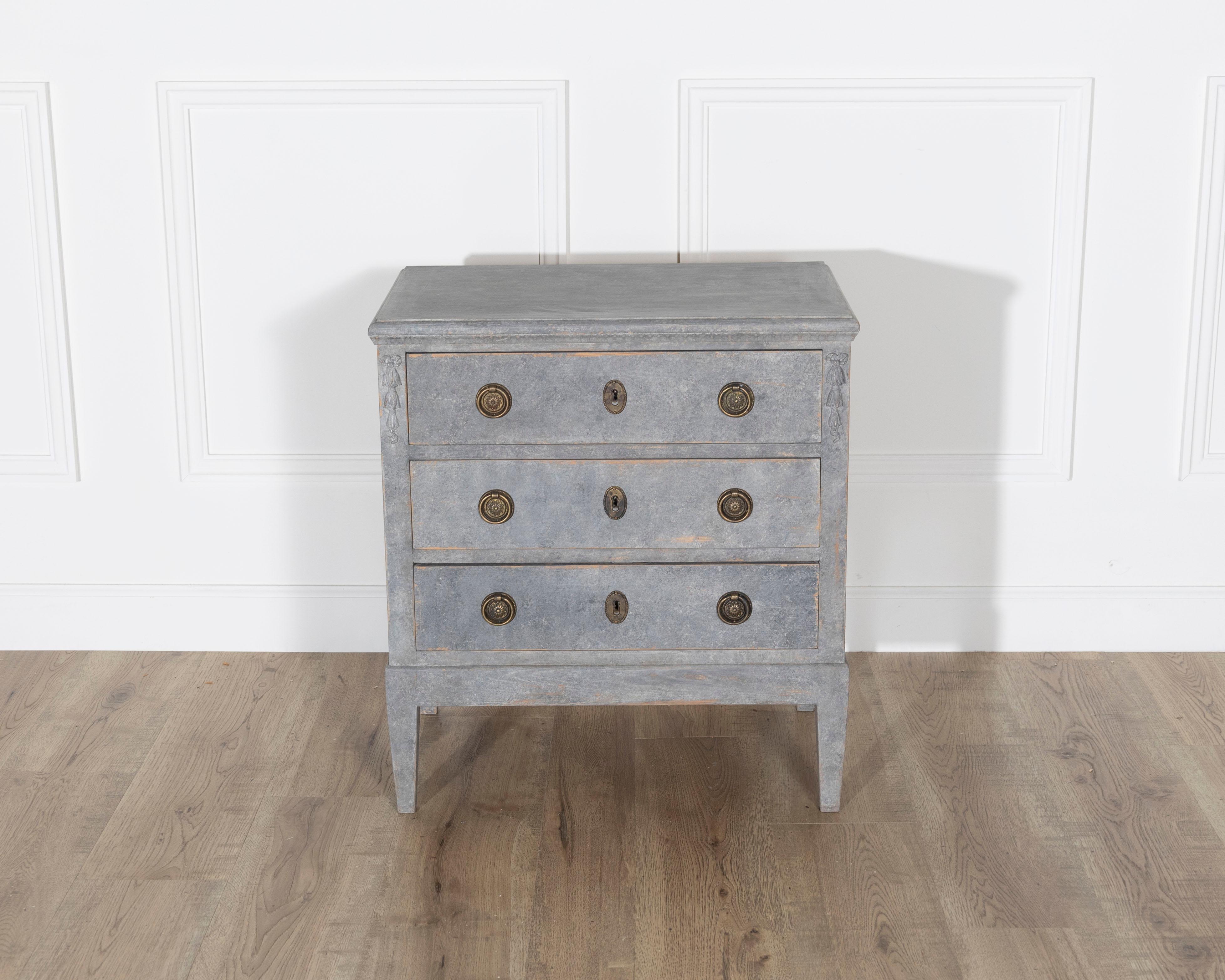 Una cassettiera svedese delicata e splendidamente invecchiata, risalente al 1920 circa, dipinta in un morbido tono grigio-blu che evoca la serena eleganza dello stile gustaviano. Questo pezzo piccolo ma maestoso poggia su alte gambe affusolate e