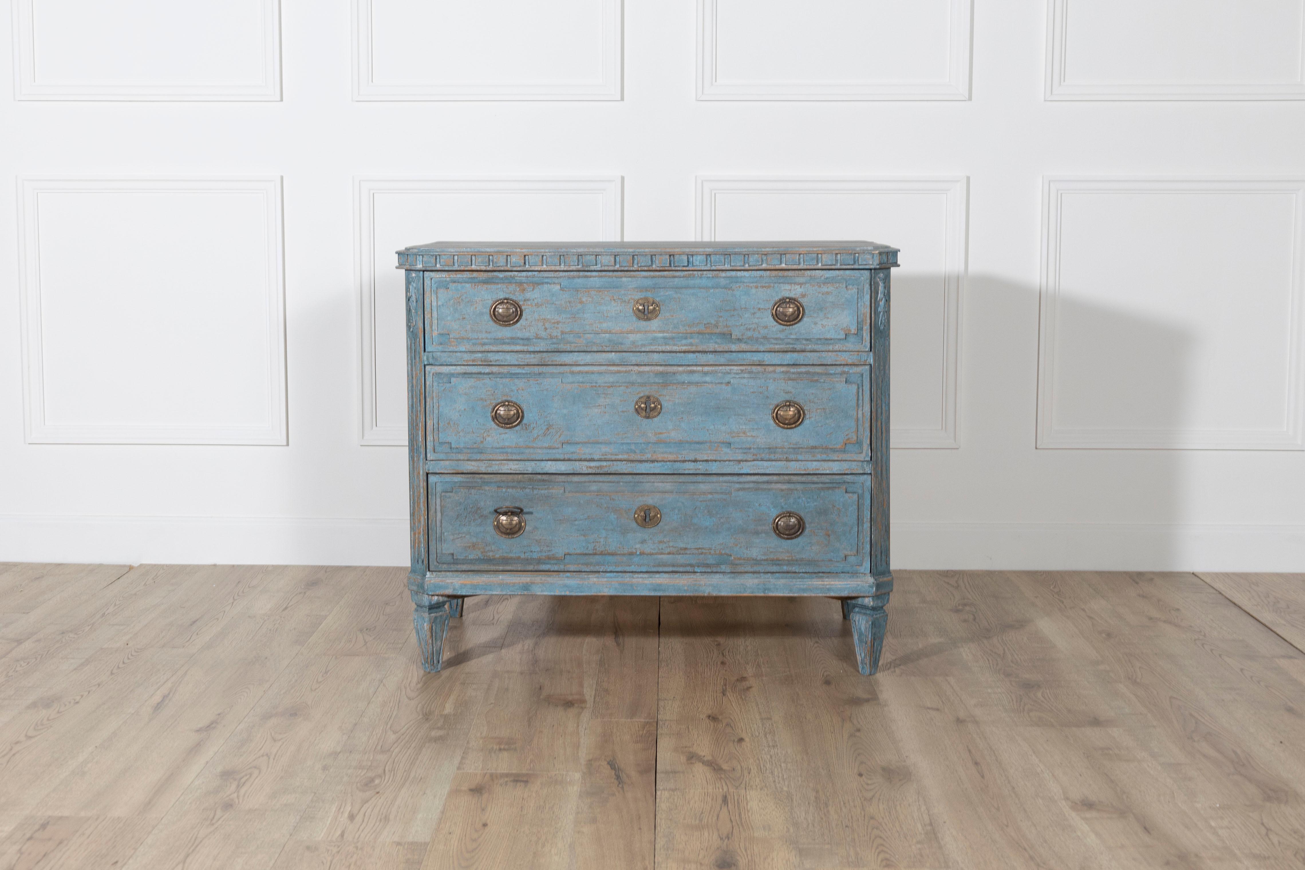 A rare and beautifully patinated Gustavian-style chest of drawers, crafted in Sweden around 1920. This three-drawer chest stands on tapered legs and features classic neoclassical detailing, including carved fluting and molding along the edges. The