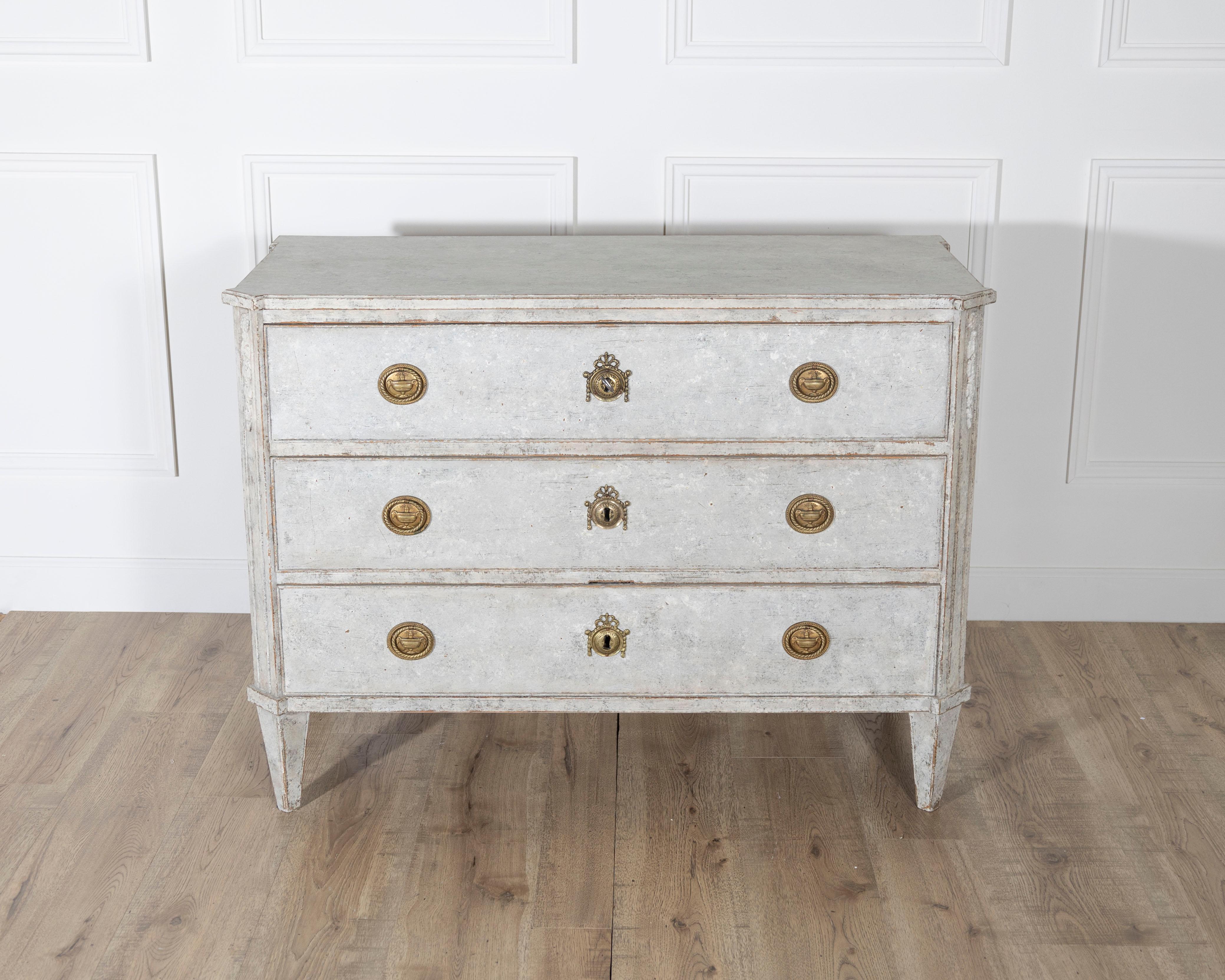 A rare and finely detailed Gustavian chest of drawers, crafted in Sweden around 1800 and finished in a soft, patinated Gustavian grey. This elegant piece stands on classic straight tapered legs and features three full-length drawers with brass
