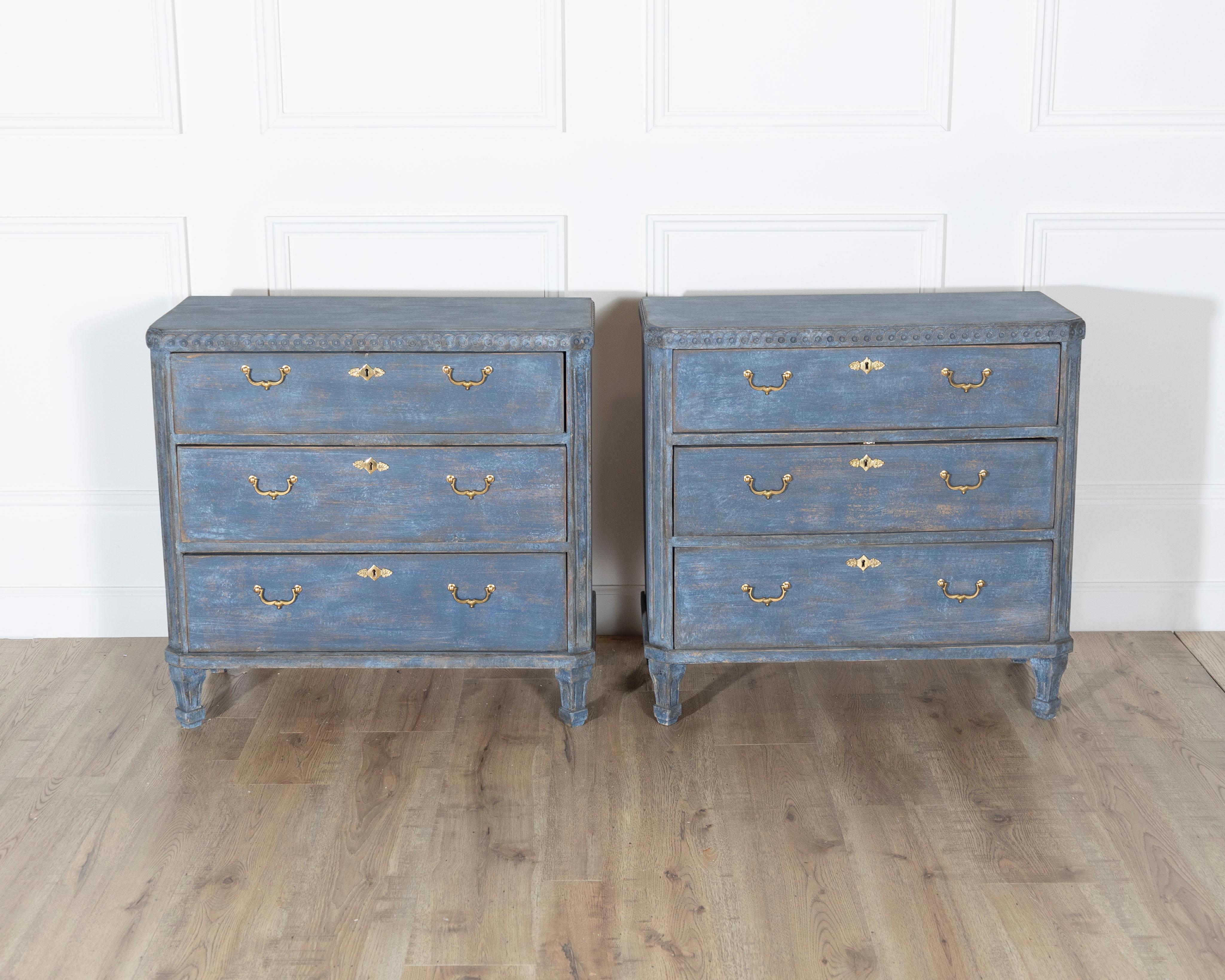 A striking pair of Swedish chests of drawers, crafted in the second half of the 19th century and finished in a richly patinated blue paint with traces of natural wood peeking through. Each chest features three spacious drawers fitted with elegant