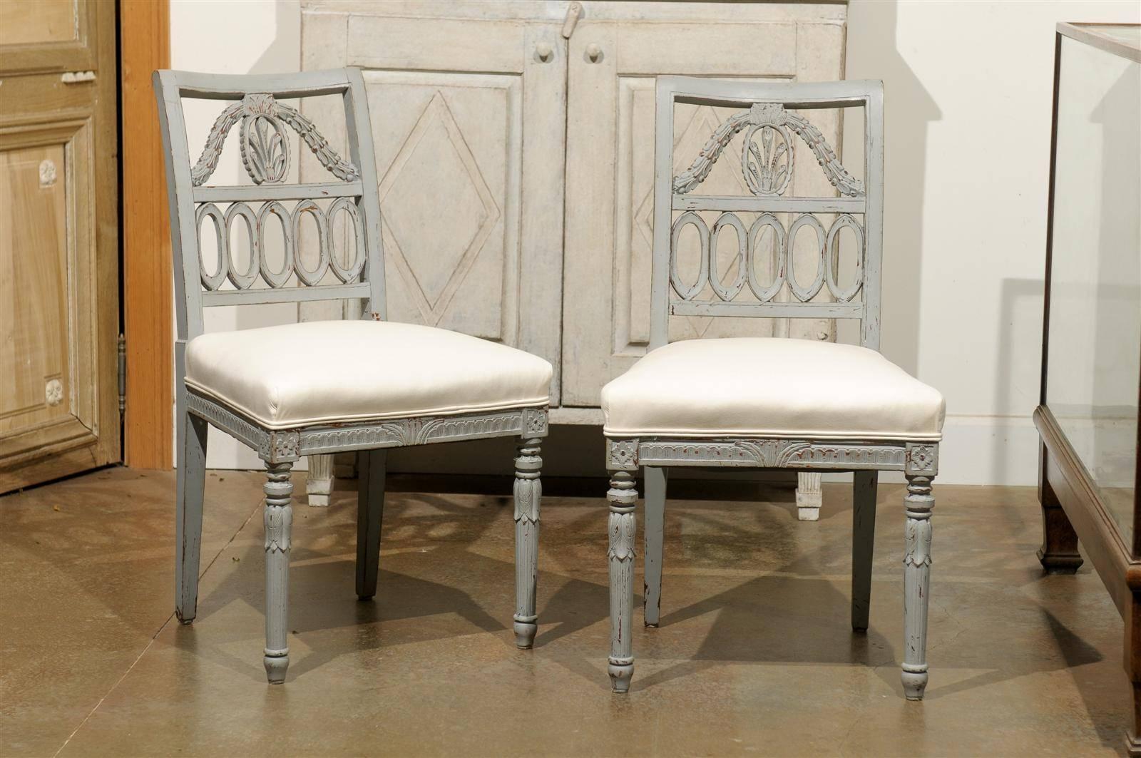 A Set of four Swedish Neoclassical style painted wood Lindome chairs from the early 20th century with upholstered seats. This set of four painted wood chairs was born in Lindome, a town from the Halland province of Sweden in the 1920s. Lindome was
