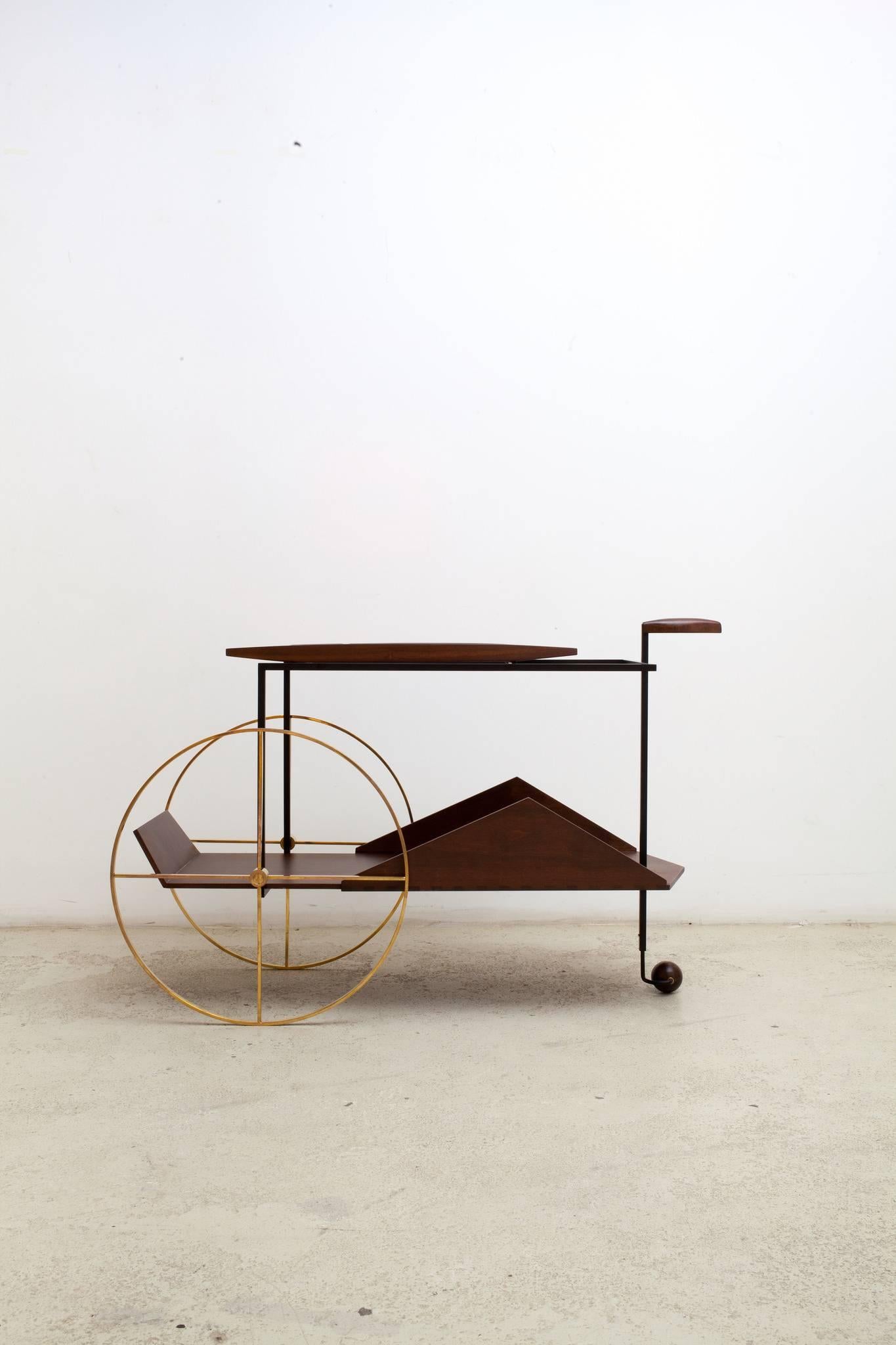 A Brazilian Modernist Classic, the 'JZ' was designed in the 1950s by Jorge Zalszupin. Its pair of slender but oversized brass wheels dramatically play off the triangle-sided bottom shelf; the tray on top is removable. Available in Honey Imbuia wood.