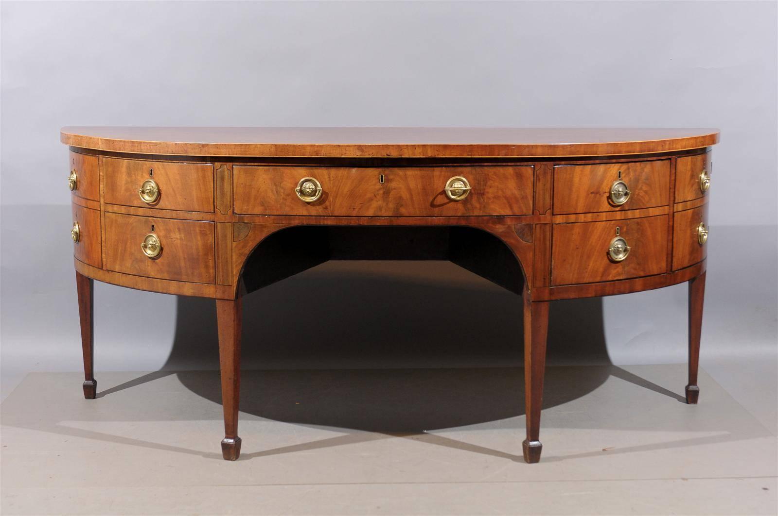 Large early 19th century English D-shaped sideboard in faded mahogany with inlay and spade feet.